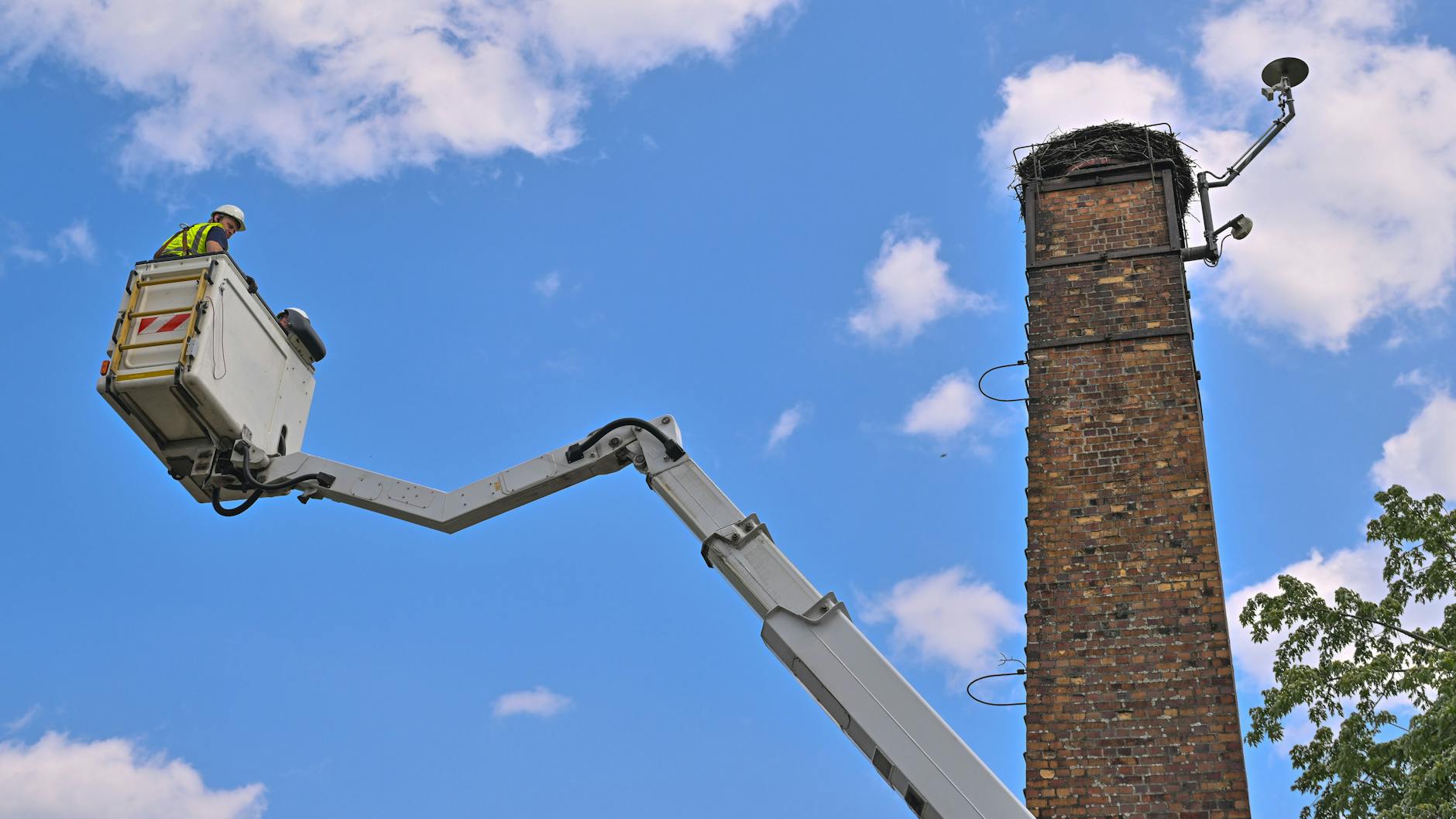 Der Elektriker Stefan Blüher fährt in einer Hebebühne zum etwa 19 Meter hohen Storchennest auf.