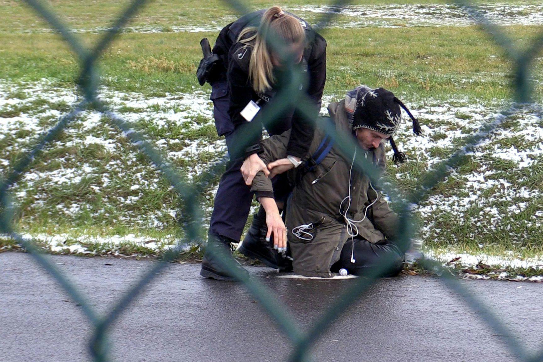 Eine Beamtin der Bundespolizei versucht einen Aktivisten der Letzten Generation von der Straße auf dem BER-Flughafen zu entfernen.