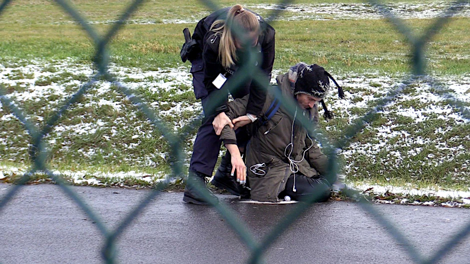 Eine Beamtin der Bundespolizei versucht einen Aktivisten der Letzten Generation von der Straße auf dem BER-Flughafen zu entfernen.