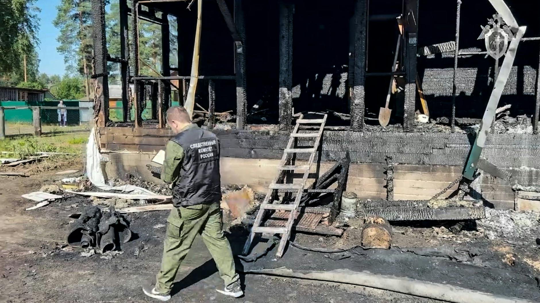 Ein Ermittler sucht an der Brandruine nach Spuren.