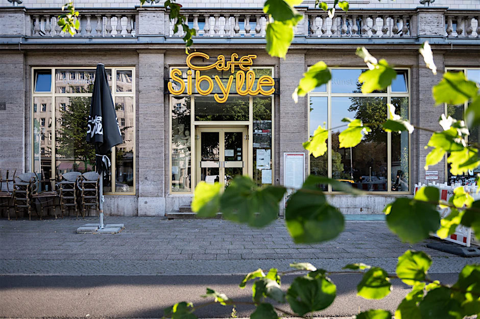 Das Café Sibylle in der Karl-Marx-Allee: links neben der Eingangstür eine Originalfigur aus dem Film „Das Leben der anderen“, rechts im Boden die Glasplatte, unter der einst ein Stadtmodell zu sehen war.