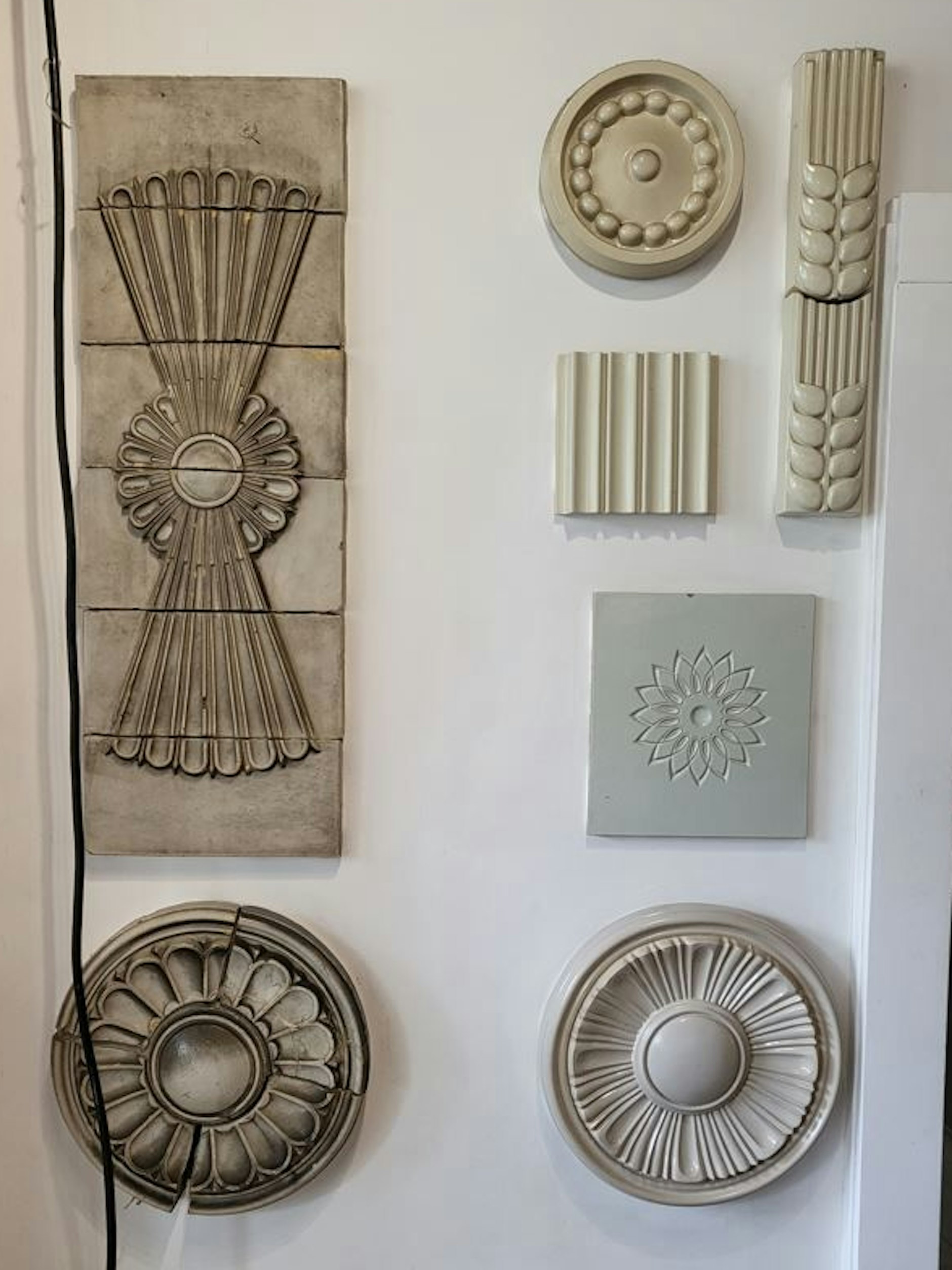 Eine Sammlung von Dekorelementen von den Bauten der Stalinallee, heute Karl-Marx-Allee. Links ein achtlos herabhängendes Kabel.