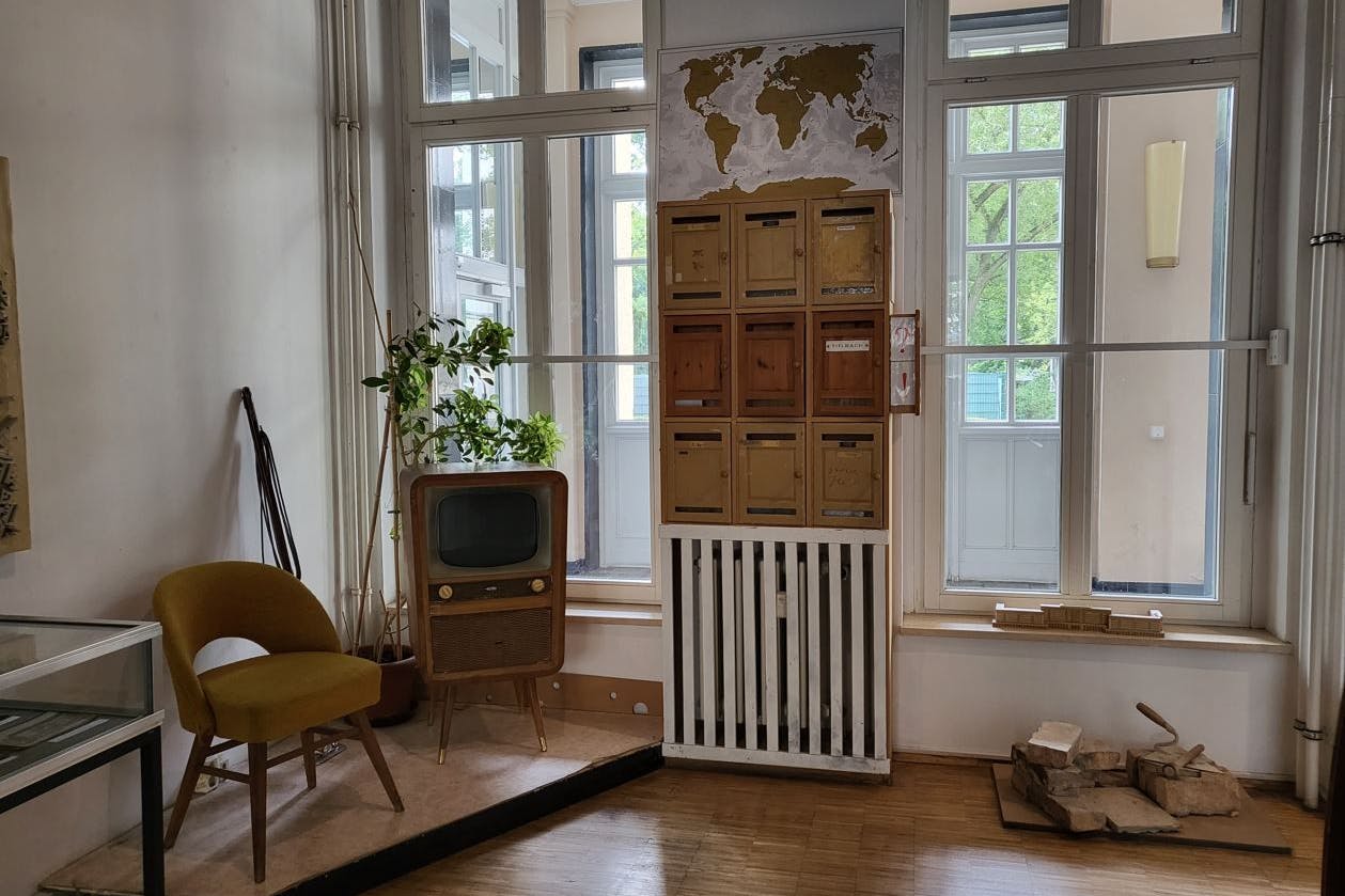 Ein noch passabel erhaltener Teil der Ausstellung im Café Sibylle zeigt eine Original-Briefkastenanlage vom Strausberger Platz und Einrichtungsgegenstände. Rechts eine Erinnerung an die Mauersteine, die aus den Trümmern gewonnen und Stein auf Stein zu den Arbeiterpalästen der Stalinallee gemauert wurden.