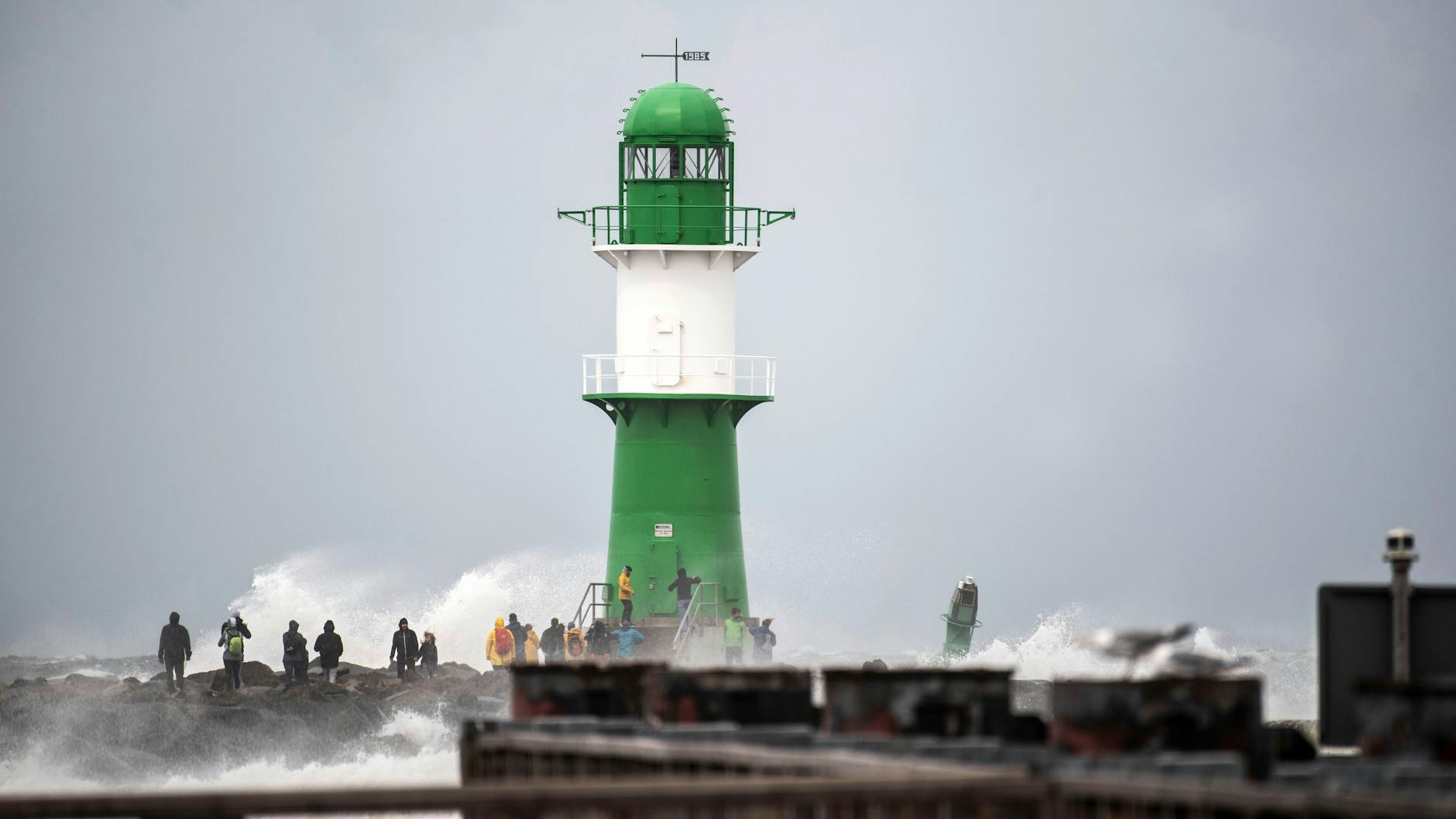 Gefährlich: Schaulustige wagen sich bei Sturm und Wellengang auf die Mole im Seebad Warnemünde.