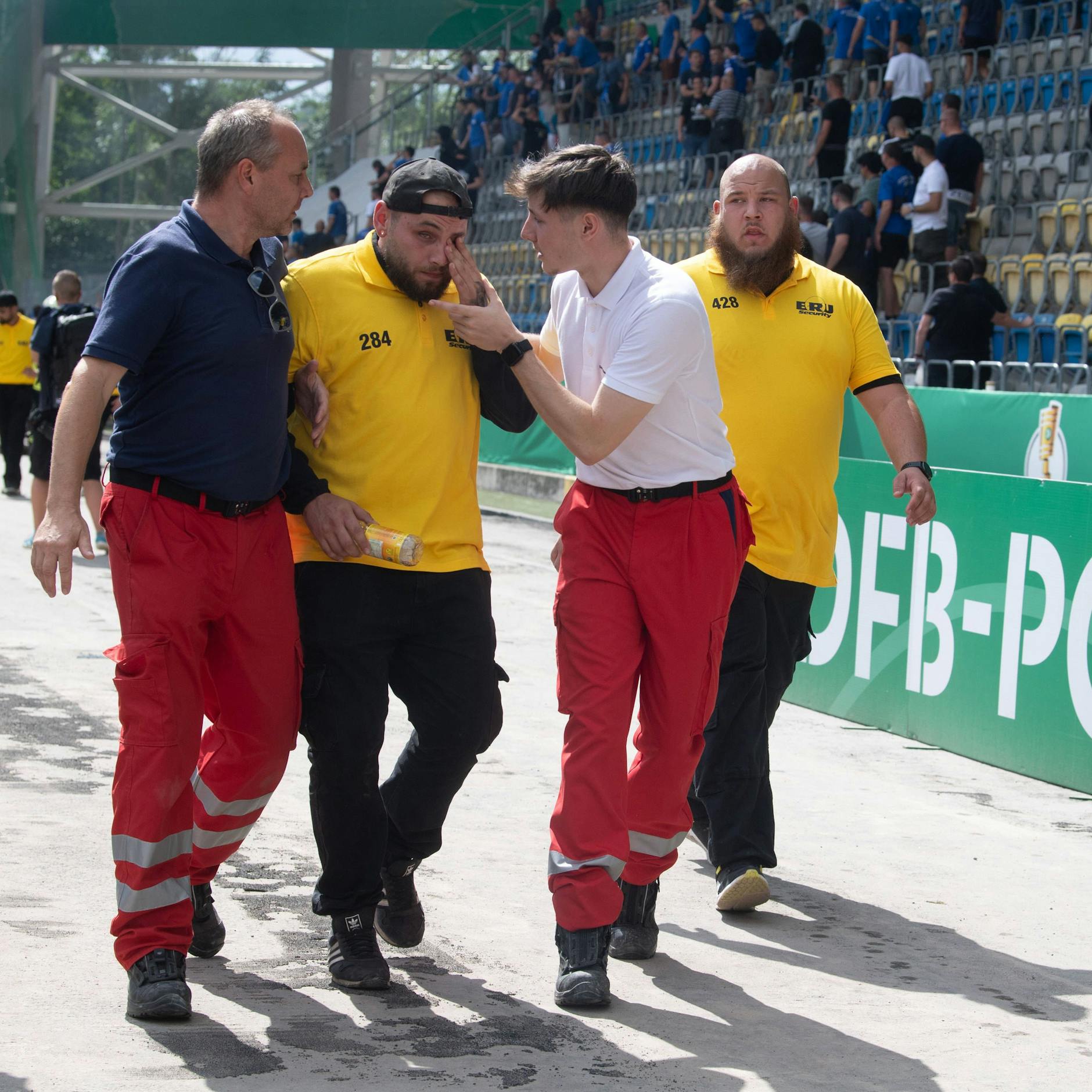Zwei Sanitäter helfen einem verletzten Ordner.