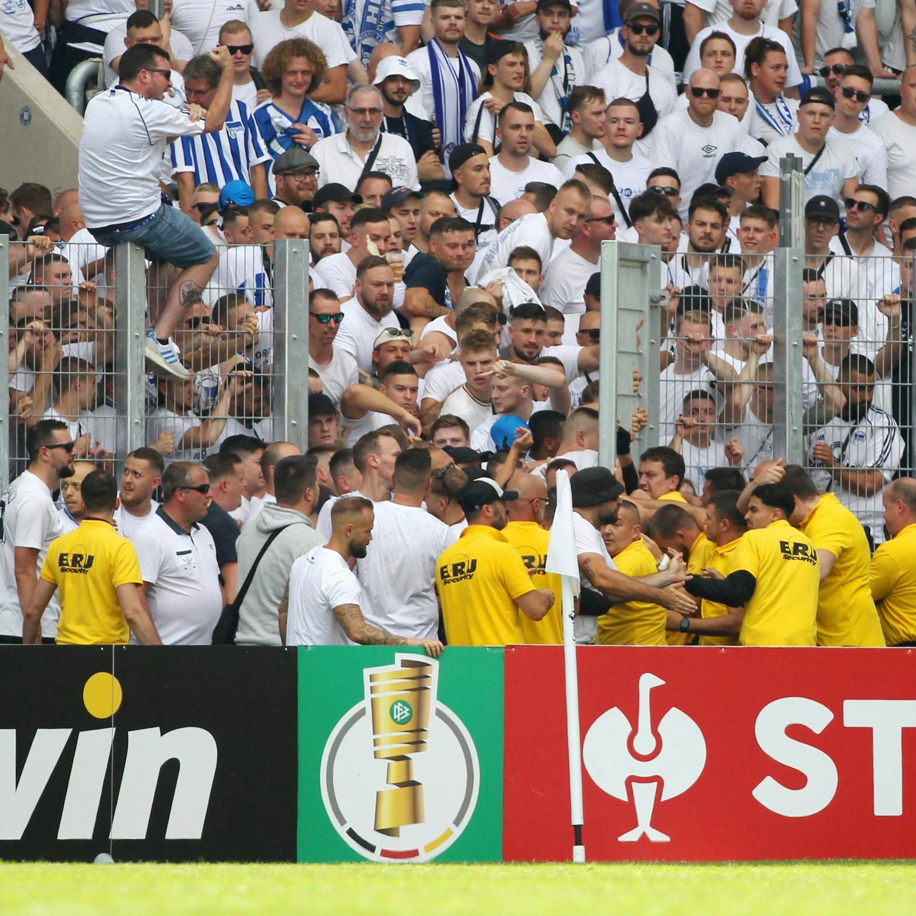 Wie konnte das Tor geöffnet werden? Herthas Fans drängen in den Innenraum und Ordner in gelben Polo-Shirts versuchen sie aufzuhalten.