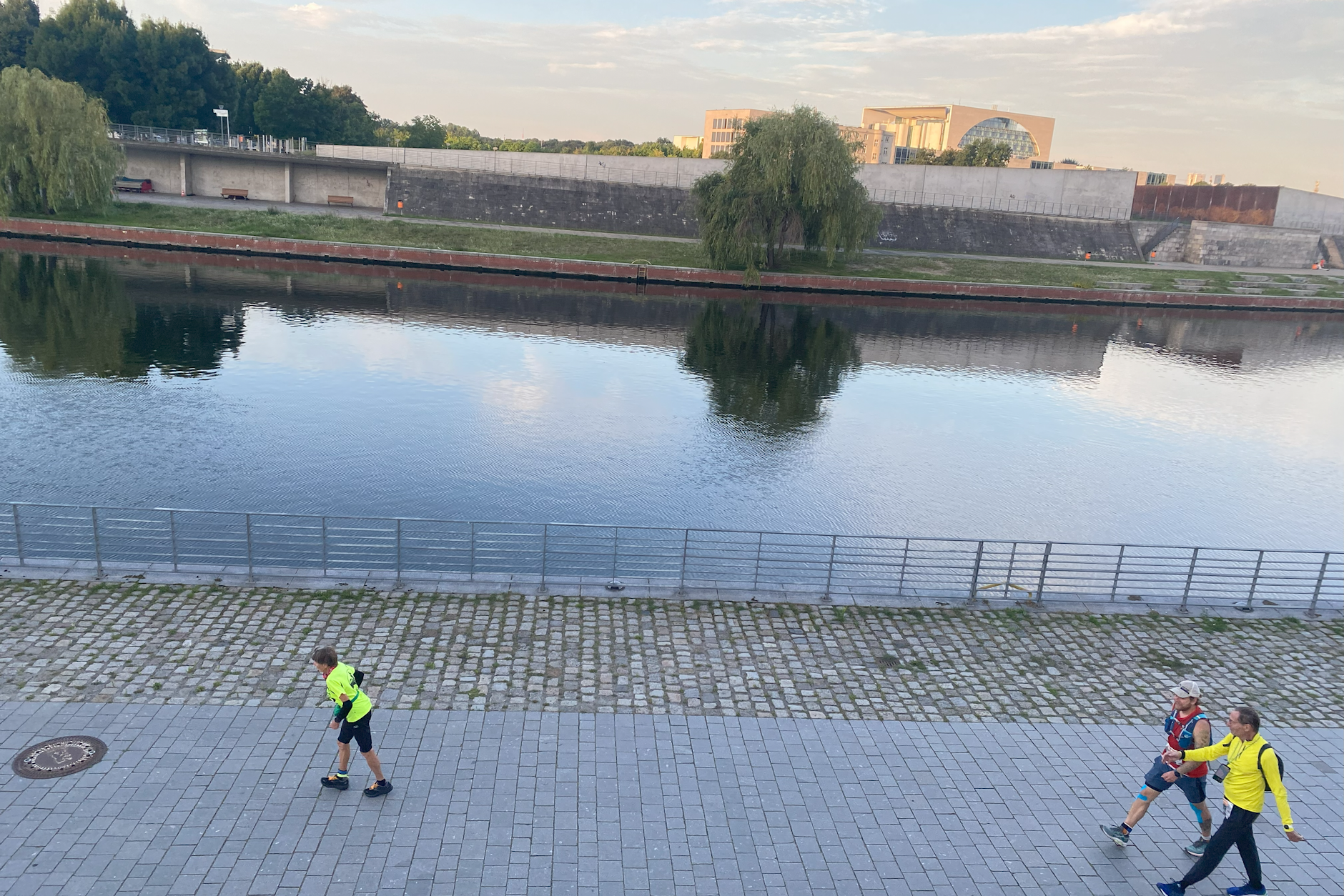 Sigrid Eichner läuft an der Spree vor den zwei Besenläufern, die den letzten Läufer begleiten.