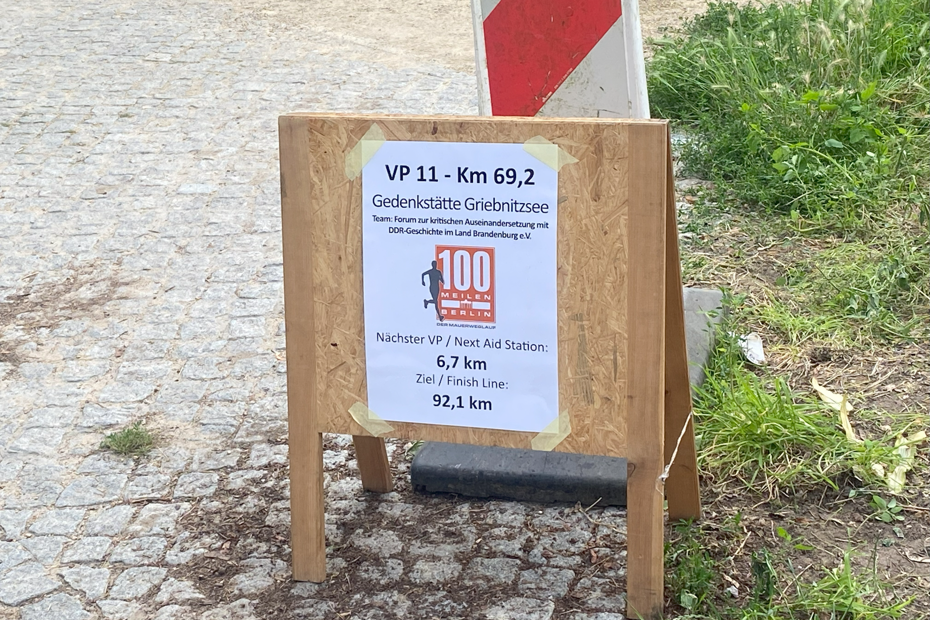 Ein Schild in Potsdam weist auf eine Verpflegungsstation entlang des 161,3 Kilometer langen Berliner Mauerweglaufs hin.