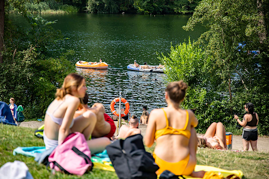 Menschen auf der Wiese und im Wasser am Schlachtensee. Kommende Woche wird es wieder über 30 Grad warm in Berlin.