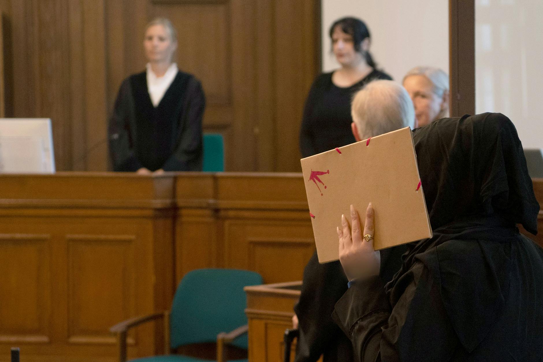 Berlin: Die Nebenklägerin (r.), Anissas Mutter, betritt einen Gerichtssaal im Kriminalgericht Moabit und verdeckt ihr Gesicht mit einem Ordner. Sie kämpft mit den Tränen.