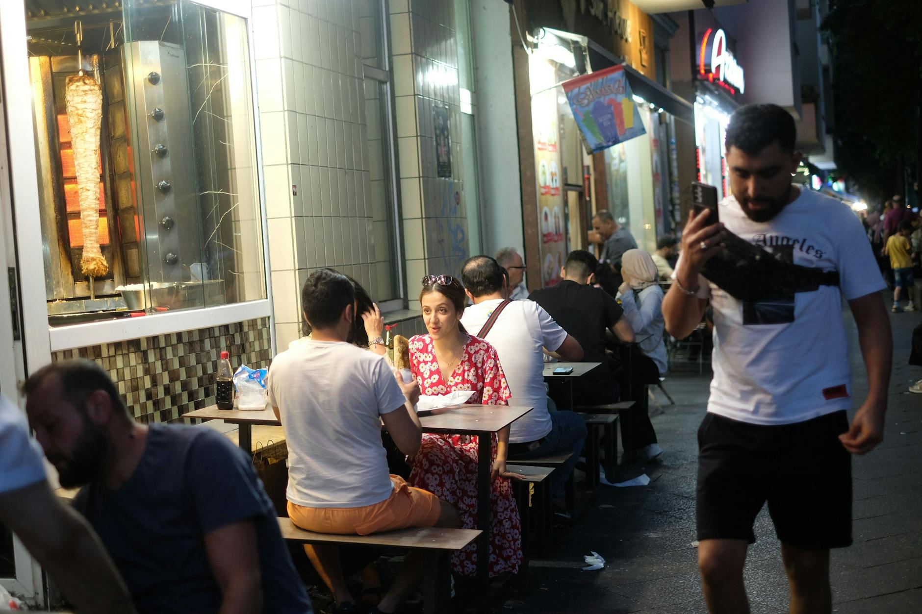 Menschen sitzen am Abend draußen vor einem Restaurant (Symbolbild).