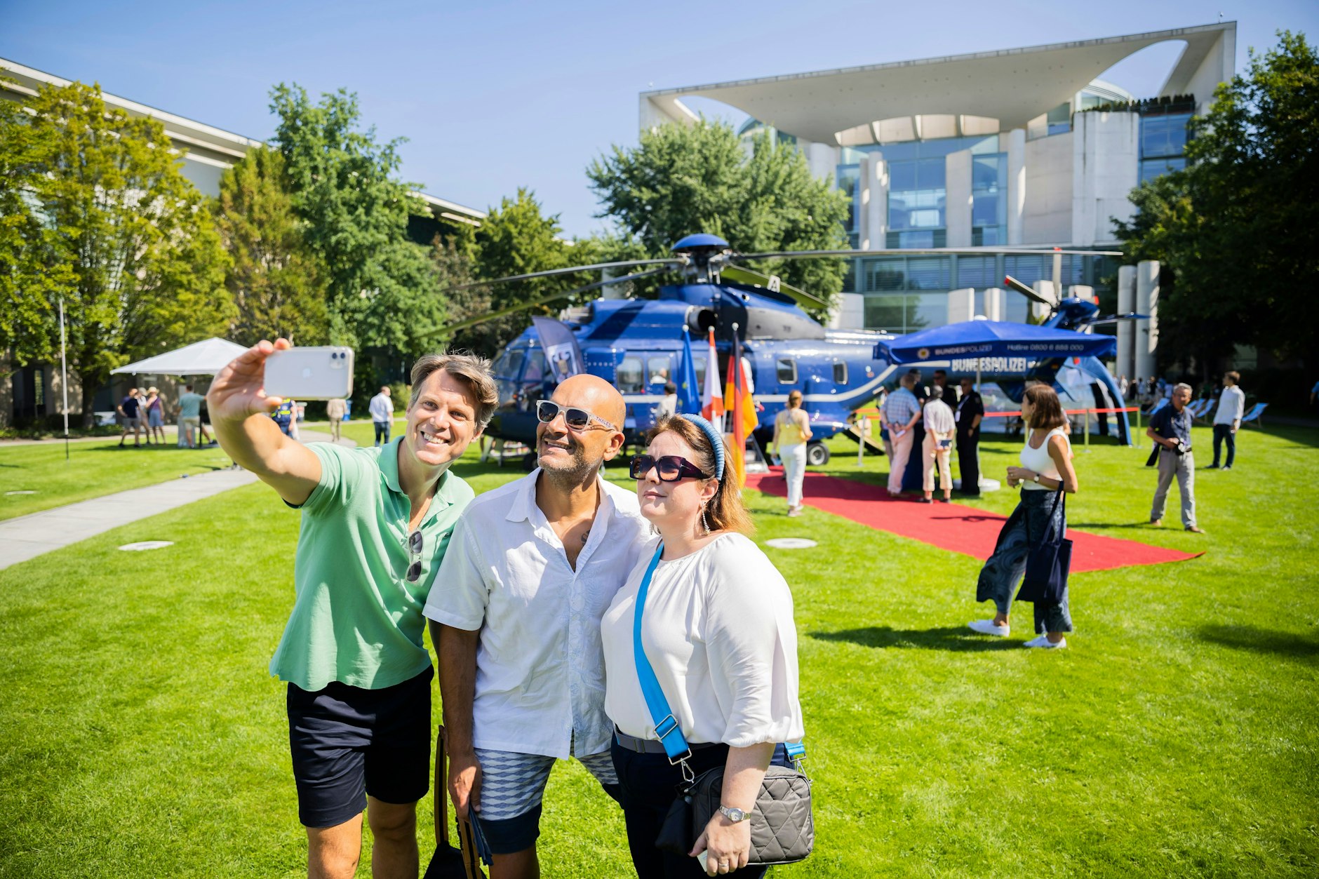 Gute Laune: Besucherinnen und Besucher machen im Garten des Bundeskanzleramts Selfies vor dem Hubschrauber der Bundespolizei.