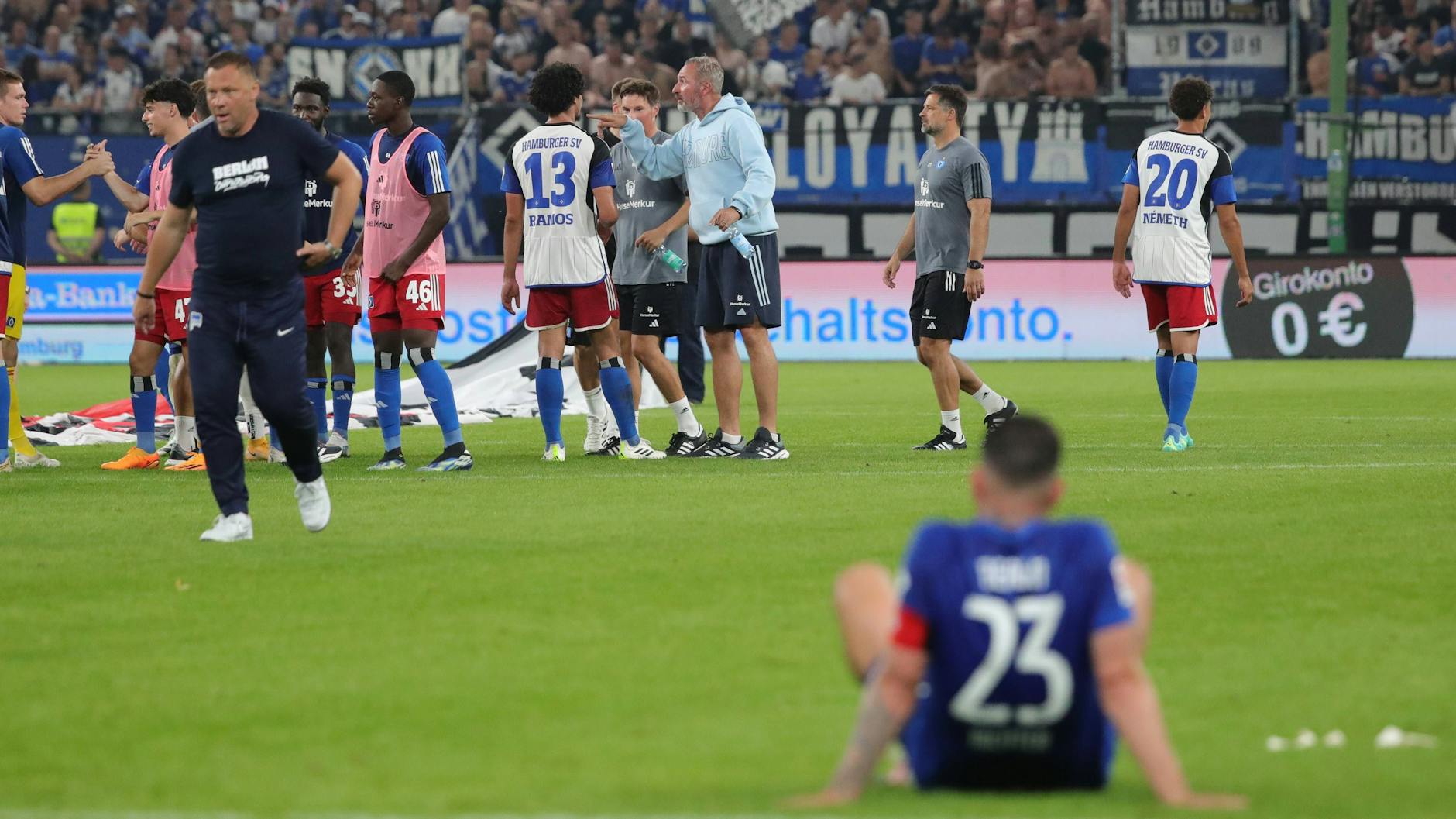 Herthas Marco Richter sitzt nach dem 0:3 in Hamburg enttäuscht auf dem Rasen, die Hamburger feiern.