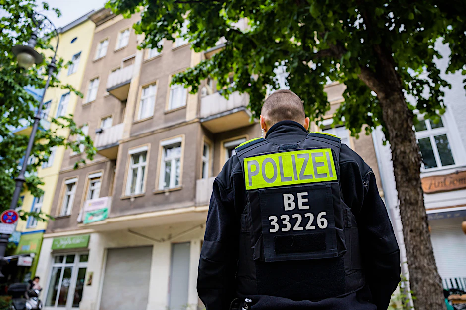 Ein Berliner Polizist steht bei einem Einsatz vor einem Wohnhaus (Symbolbild).&nbsp;