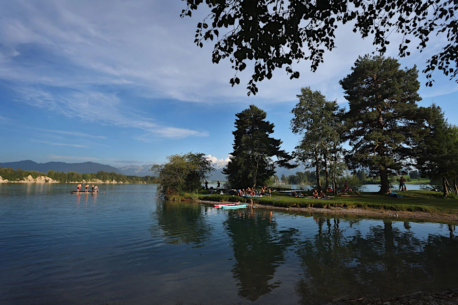 Badegäste suchen Abkühlung in einer Bucht am Forggensee in Bayern.  