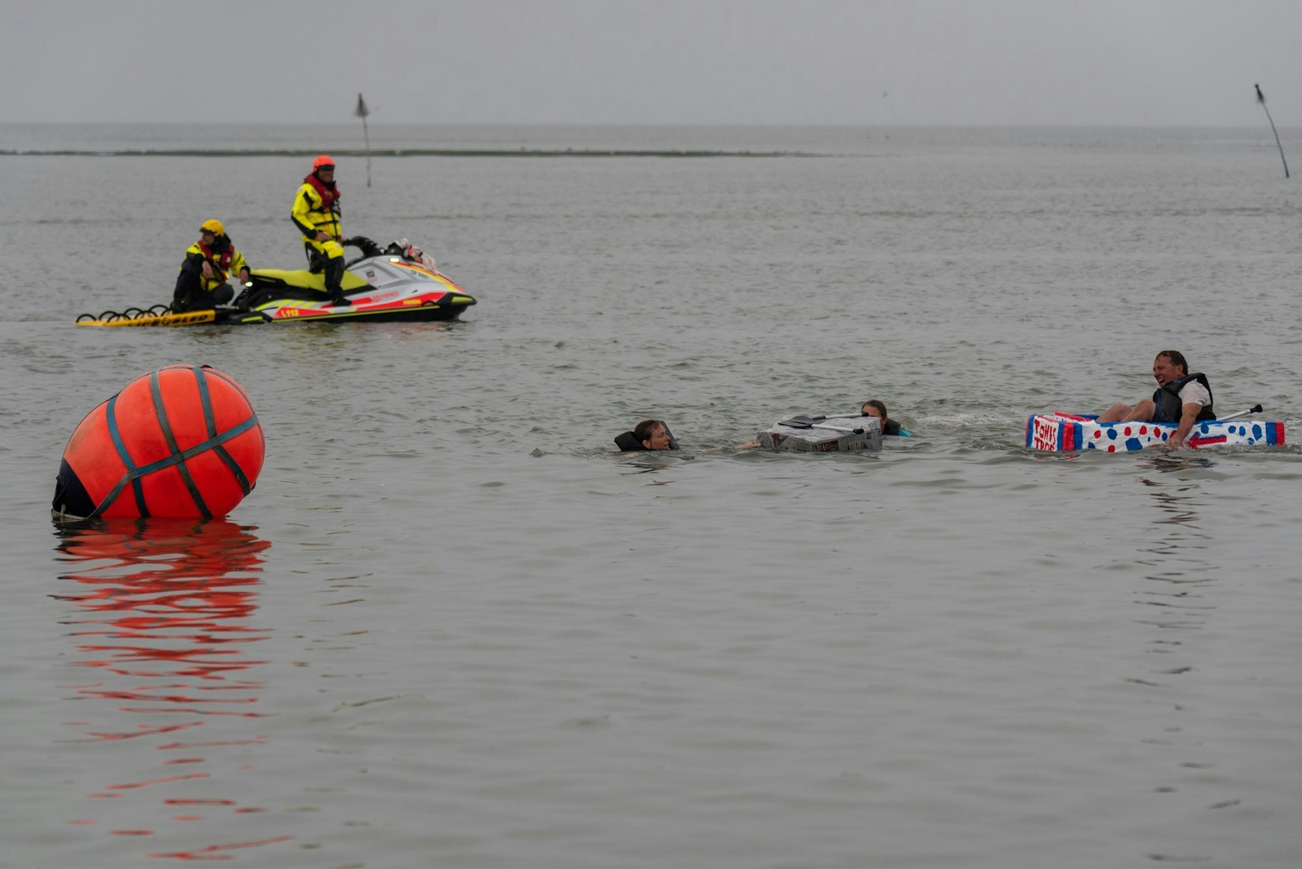 HANDOUT - Mit selbstgebauten Booten paddeln Teilnehmer der traditionellen Papierbootregatta auf Spiekeroog durch einen Parcours im Hafen der ostfriesischen Insel - nicht alle Boote blieben dabei unversehrt.  g/dpa