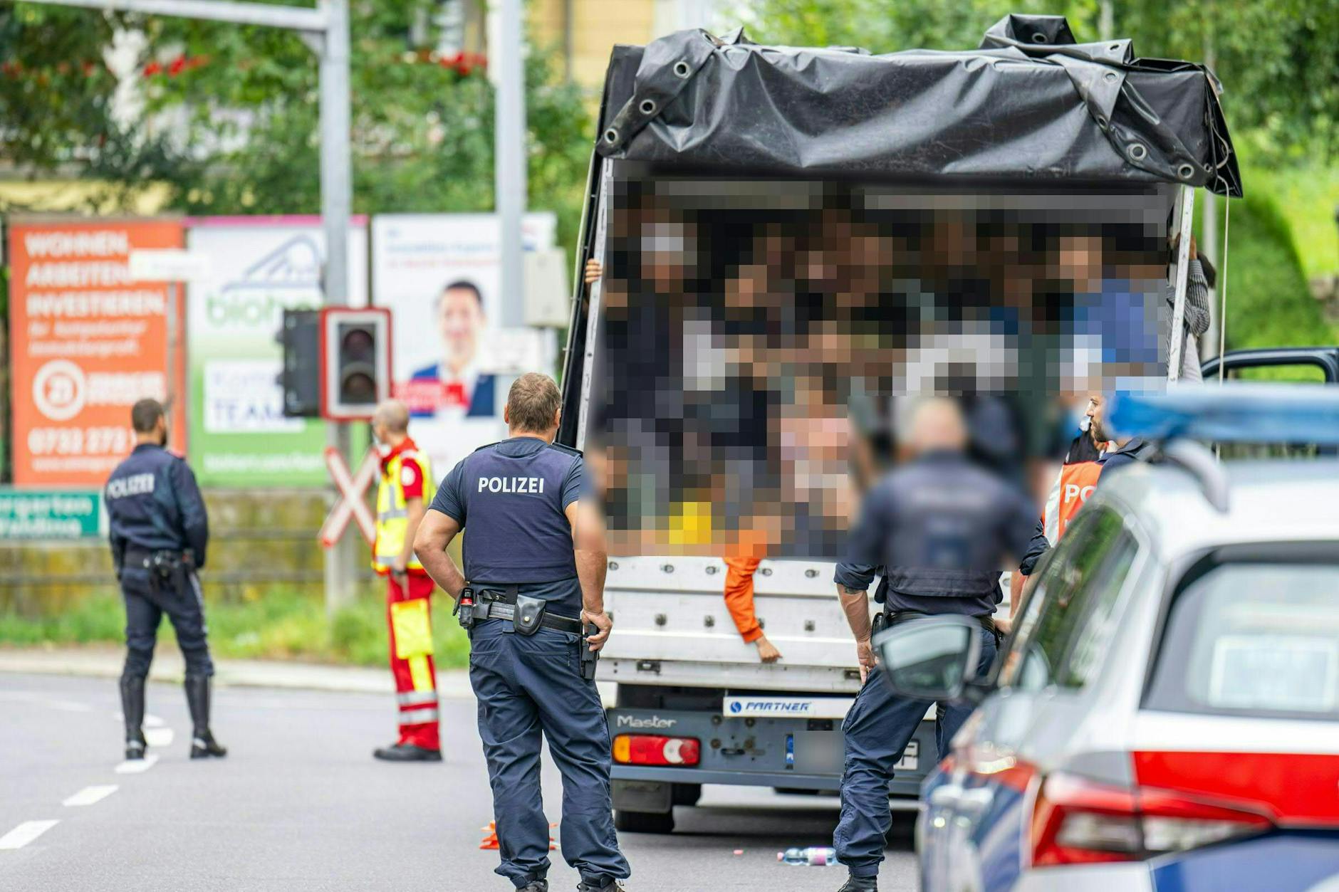 Polizisten stehen an einem Kleintransporter. Die Beamten entdeckten 53 Personen auf der Ladefläche, unter ihnen mehrere Kinder (gepixelt).