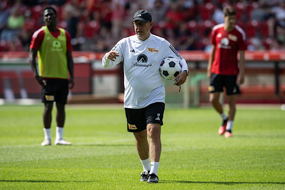 Unions Trainer Urs Fischer trägt einen Fußball unter dem Arm während des Trainings.  