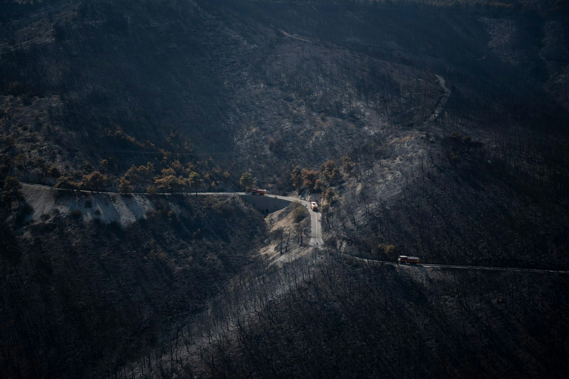 dpatopbilder - Griechenland kommt nicht zur Ruhe: Waldbrände wütend weiterhin in mehreren Teile des Landes. Feuerwehrautos fahren hier über eine Straße in einem verbrannten Wald in der Nähe von Athen.  