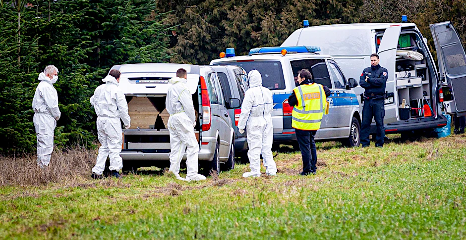 Mitarbeiter der Spurensicherung der Polizei stehen an einem Leichenwagen, der auf einer Wiese in Wunstorf parkt. In der Nähe wurde im Januar die Leiche eines 14-Jährigen gefunden.