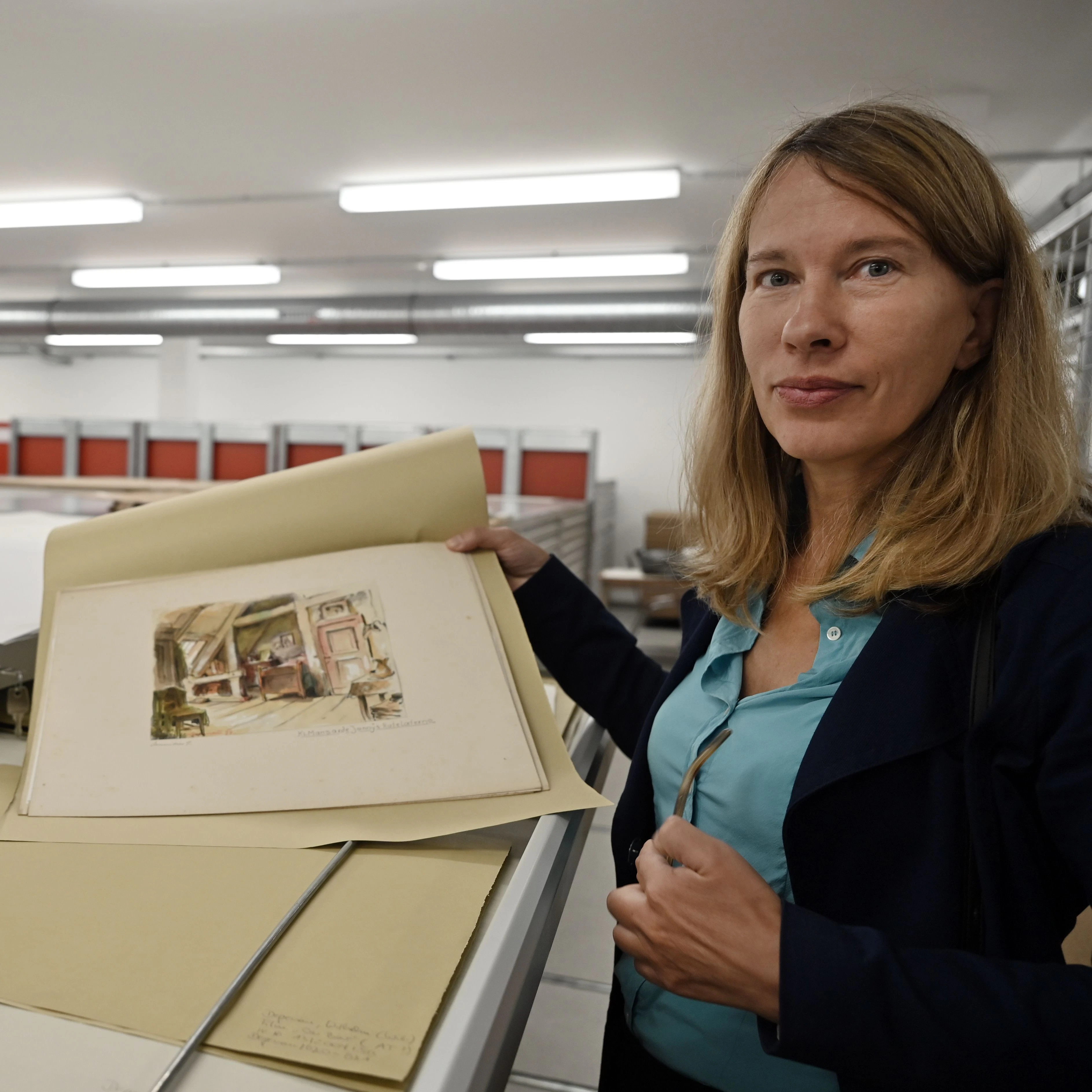 Ilka Brombach, wissenschaftlich-kuratorische Leitung des Filmmuseums Potsdam, zeigt im neuen Archiv des Museums ein Szenenbild von Willi Depenau. 