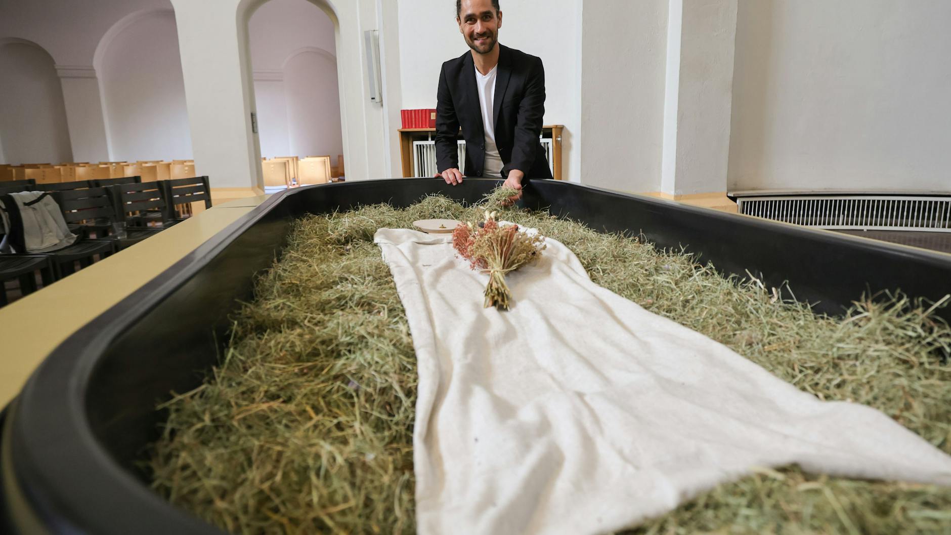 Pablo Metz von „Meine Erde“ steht vor einem Kokon, in den der Leichnam auf Heu, Stroh und Grünschnitt gebettet und in 40 Tagen zu Erde wird.