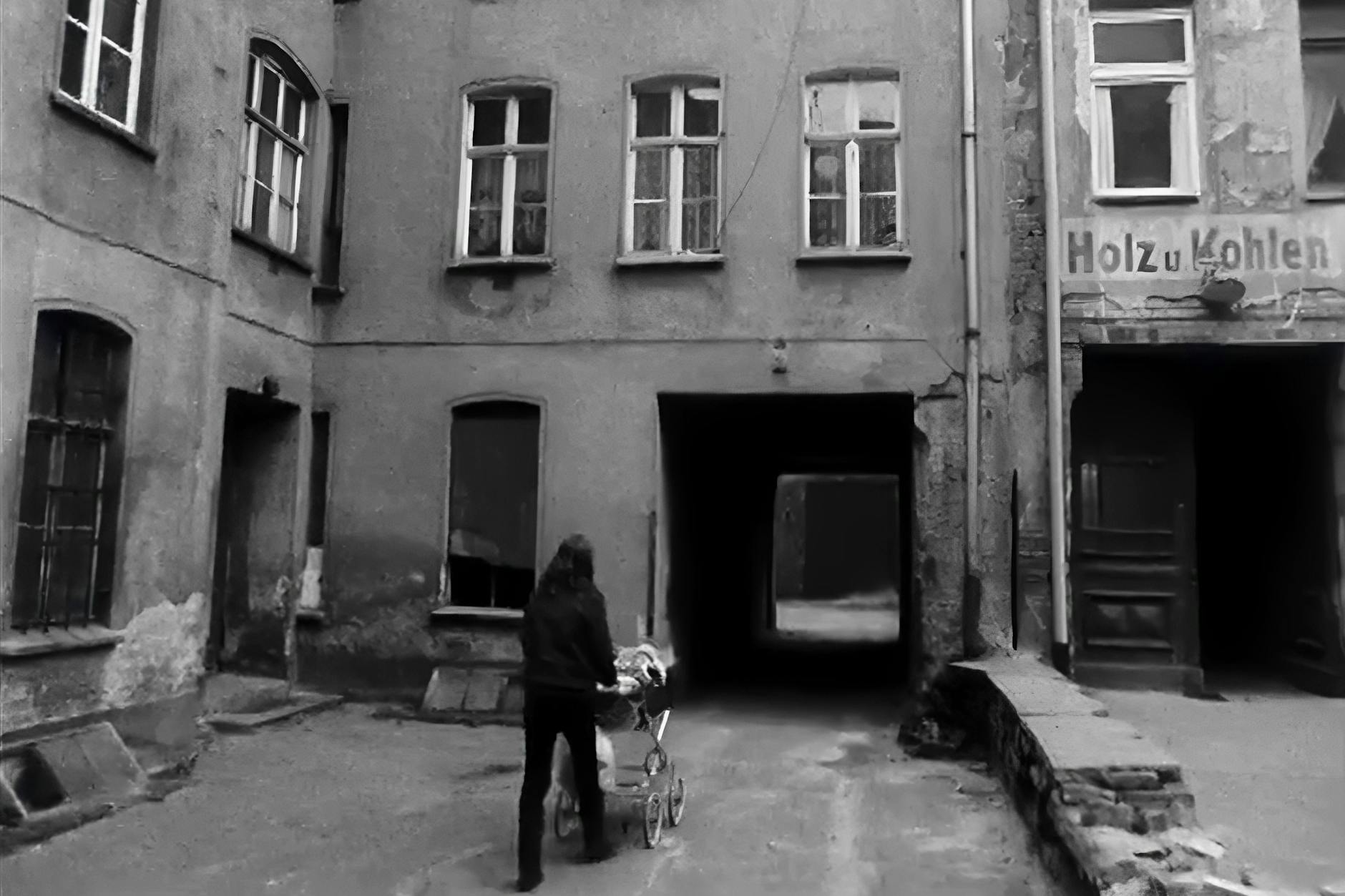 Eine Frau schiebt einen Kinderwagen durch einen Hinterhof in Berlin.