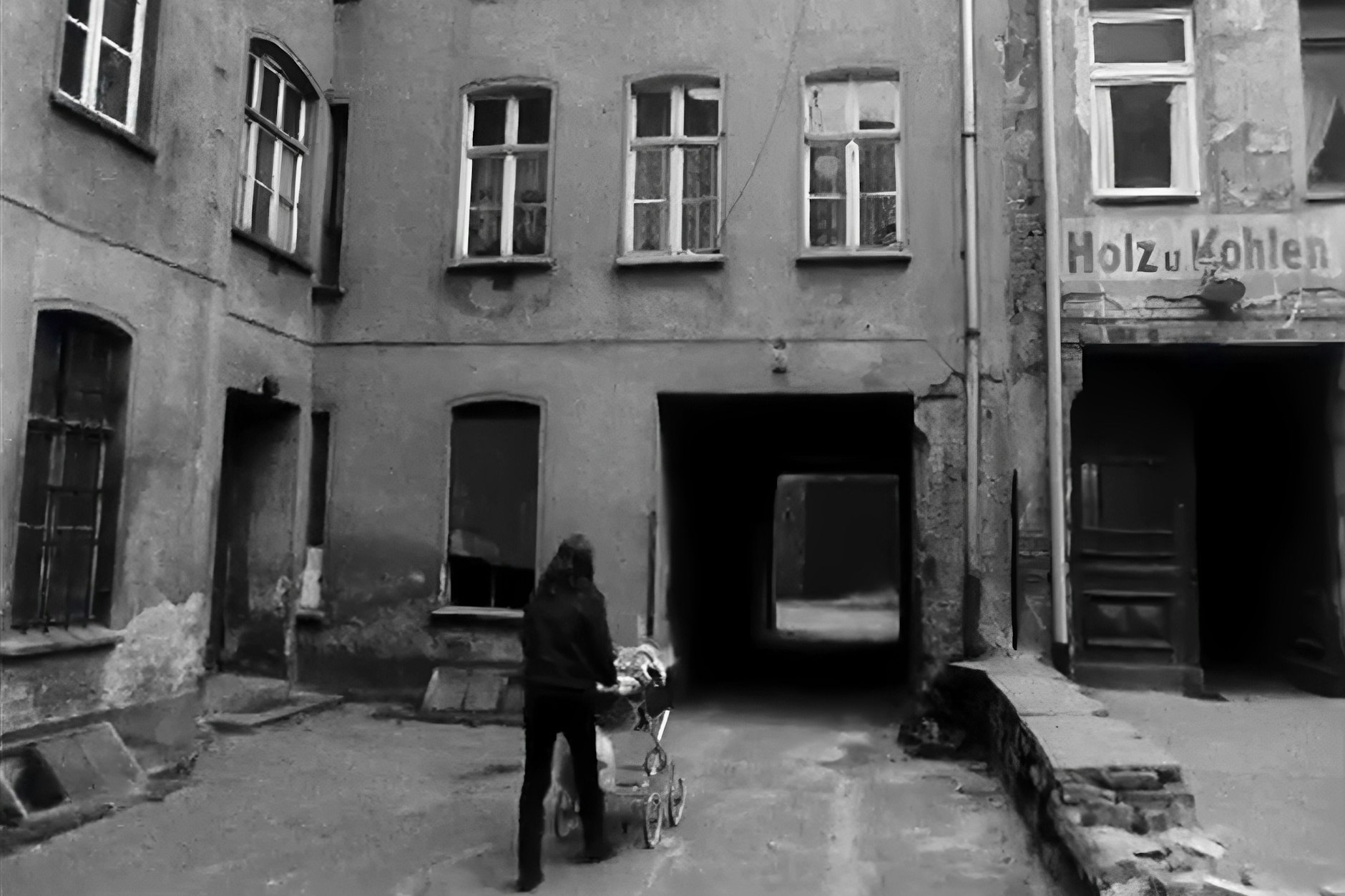 Eine Frau schiebt einen Kinderwagen durch einen Hinterhof in Berlin.