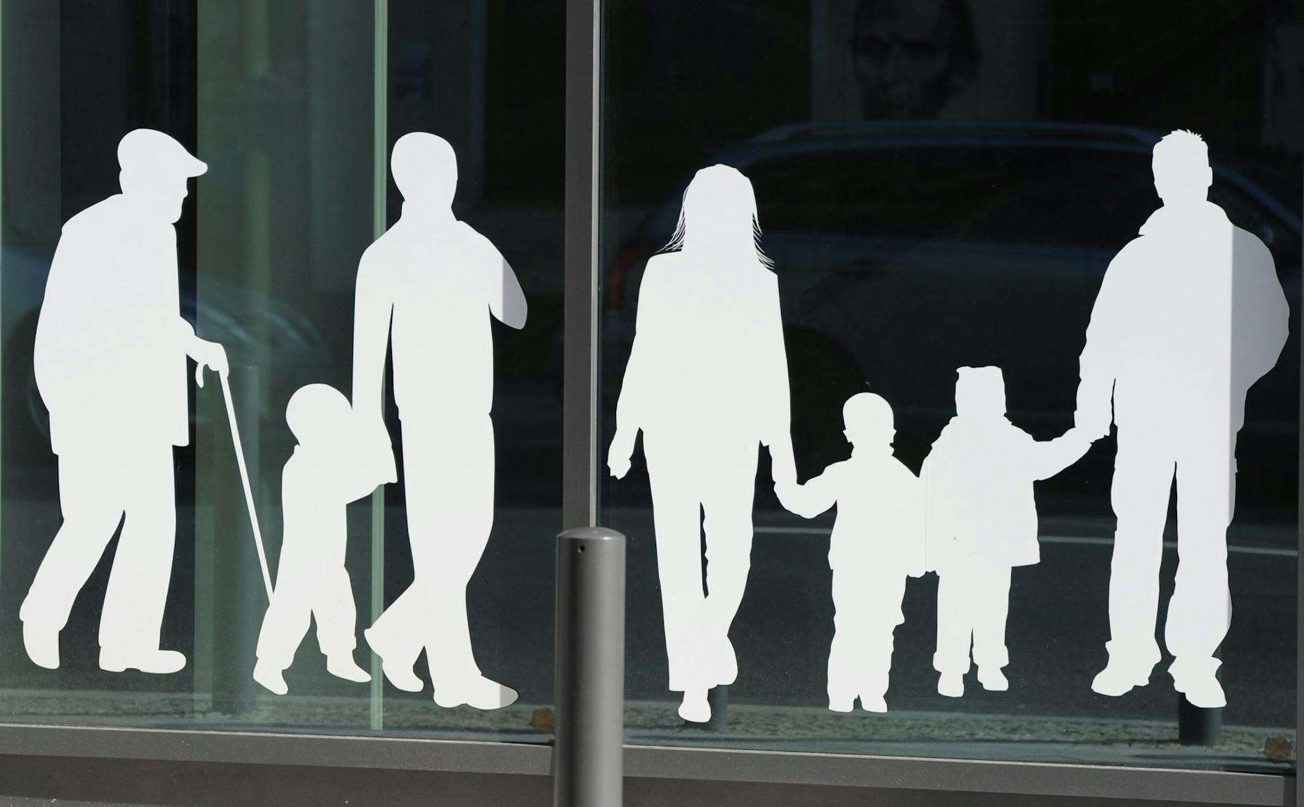 ARCHIV - Figuren von Menschen in verschiedenem Alter sind auf Fensterscheiben aufgeklebt. /Archivbild