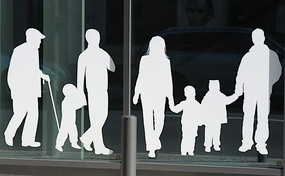 ARCHIV - Figuren von Menschen in verschiedenem Alter sind auf Fensterscheiben aufgeklebt.  /Archivbild
