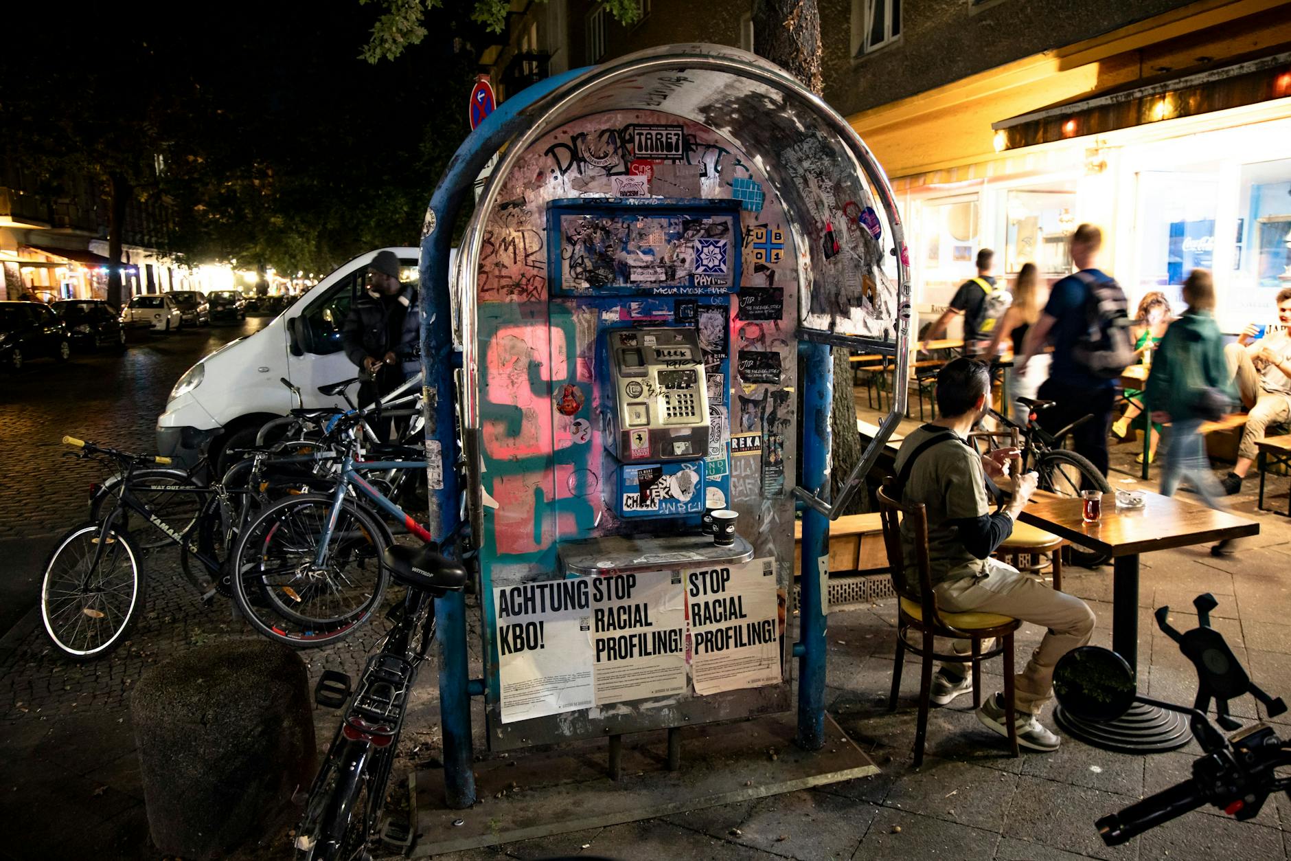 Plakate „Achtung KBO!“ und „Stop racial profiling!“ auf einer alten Telefonzelle im Wrangelkiez.