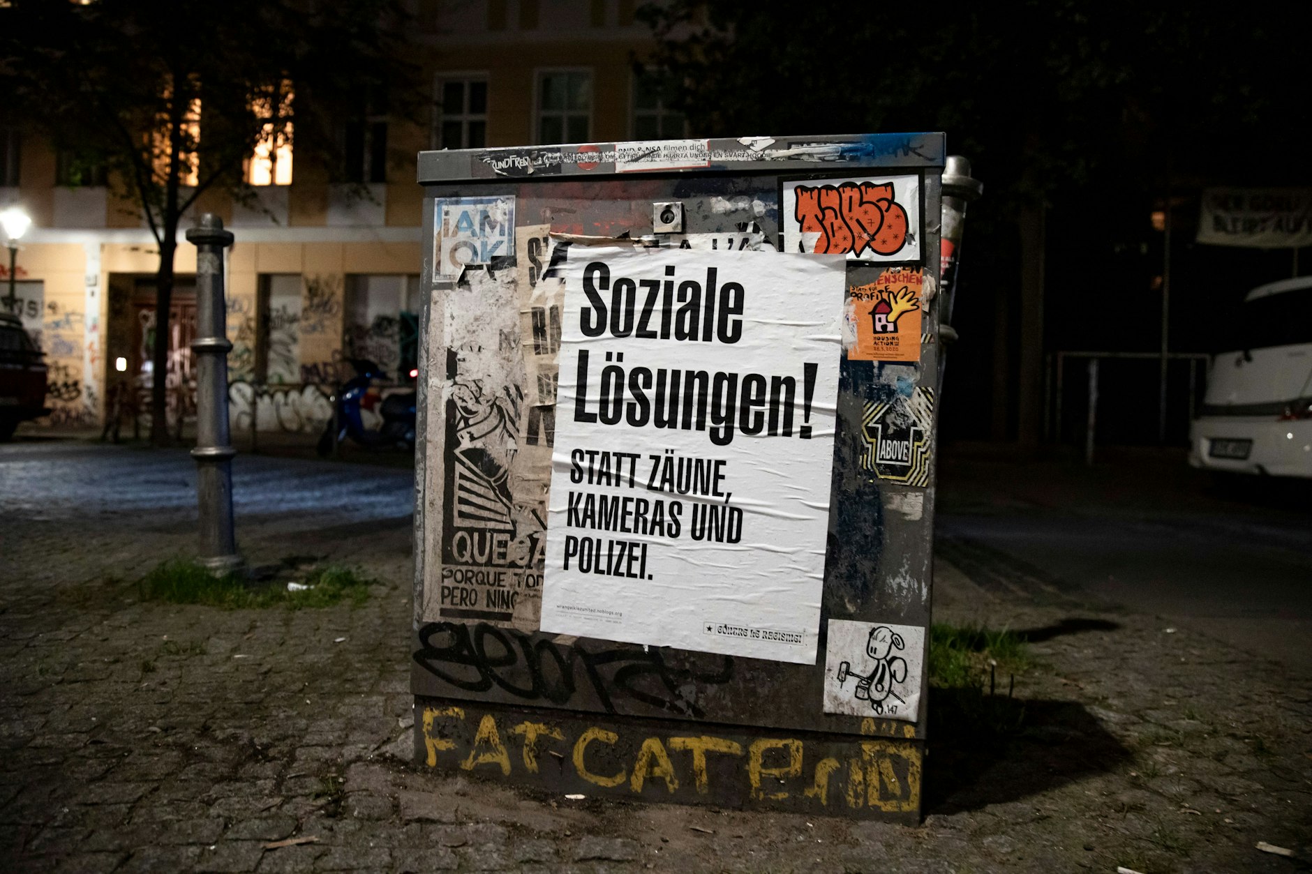 Ein Plakat zeigt den Slogan: „Soziale Lösungen, statt Zäune, Kameras und Polizei“ im Wrangelkiez.