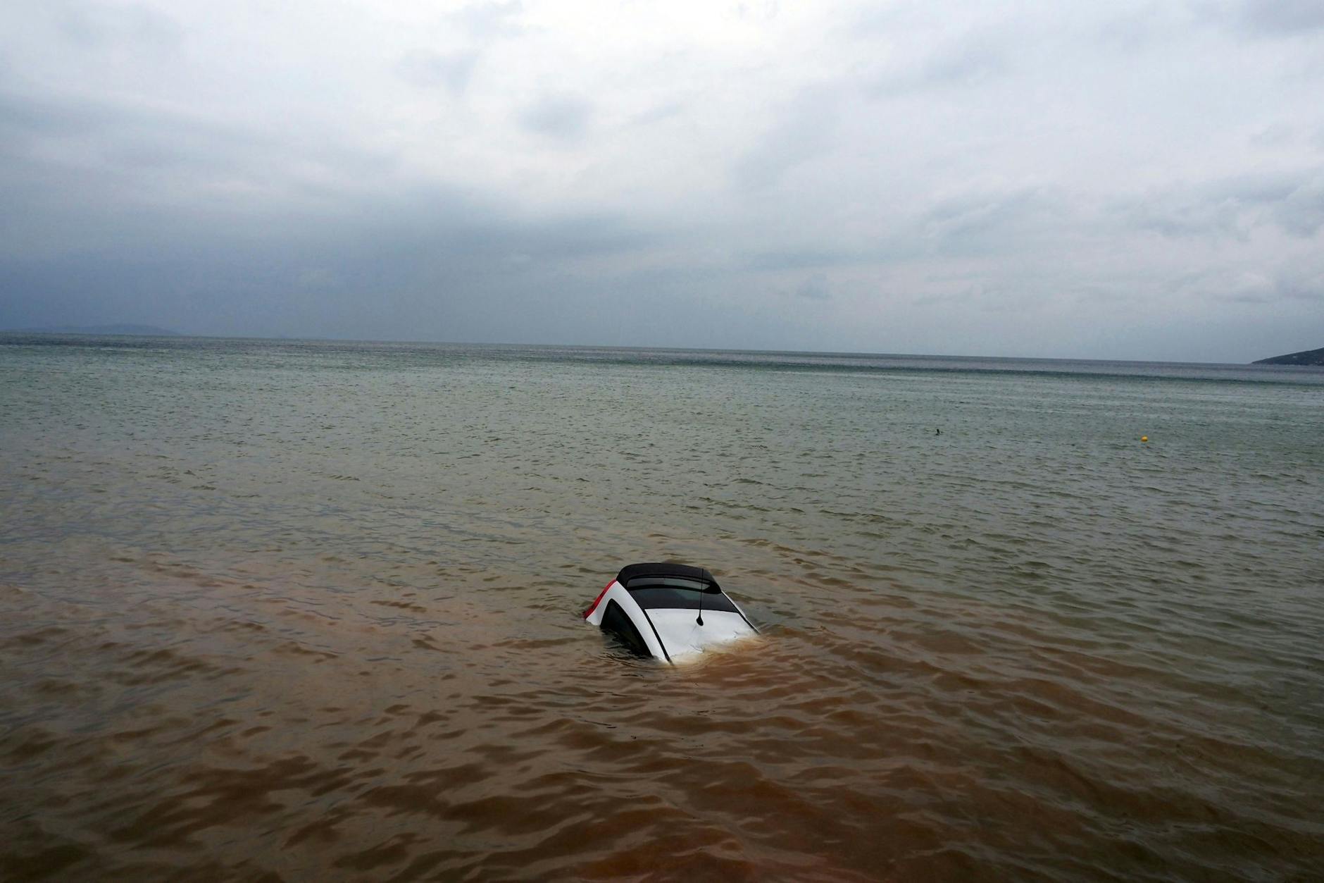 Ein Auto ist nach einem Rekordregen in Milina fast ganz im Meer versunken.