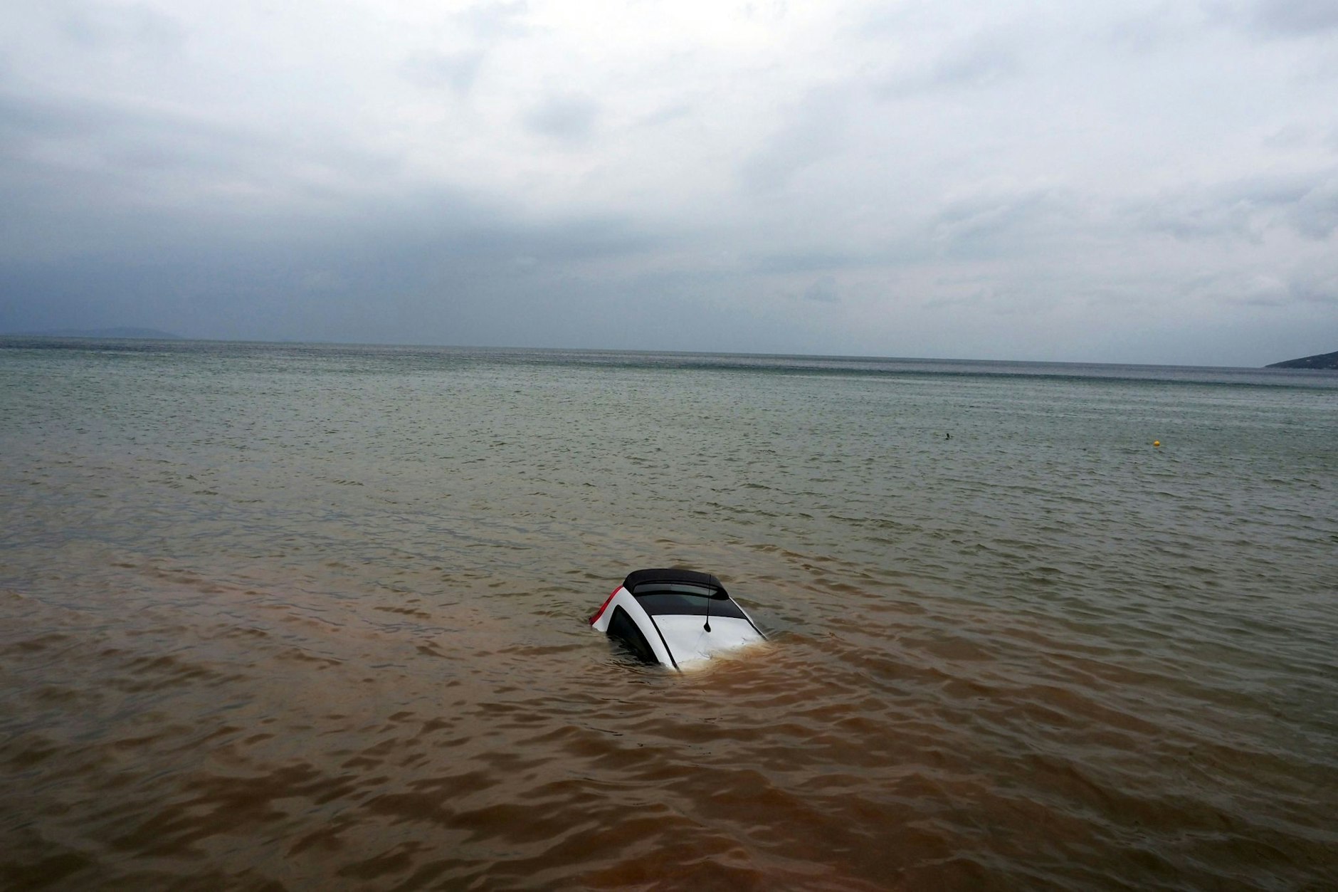 Ein Auto ist nach einem Rekordregen in Milina fast ganz im Meer versunken.  