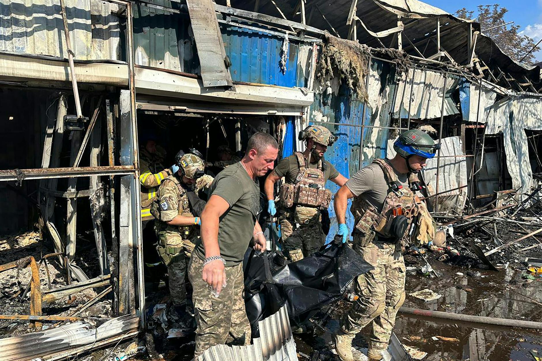 Soldaten und Rettungskräfte tragen die Leiche eines Opfers nach einem russischen Raketenangriff auf einen Markt in der Region Donezk.