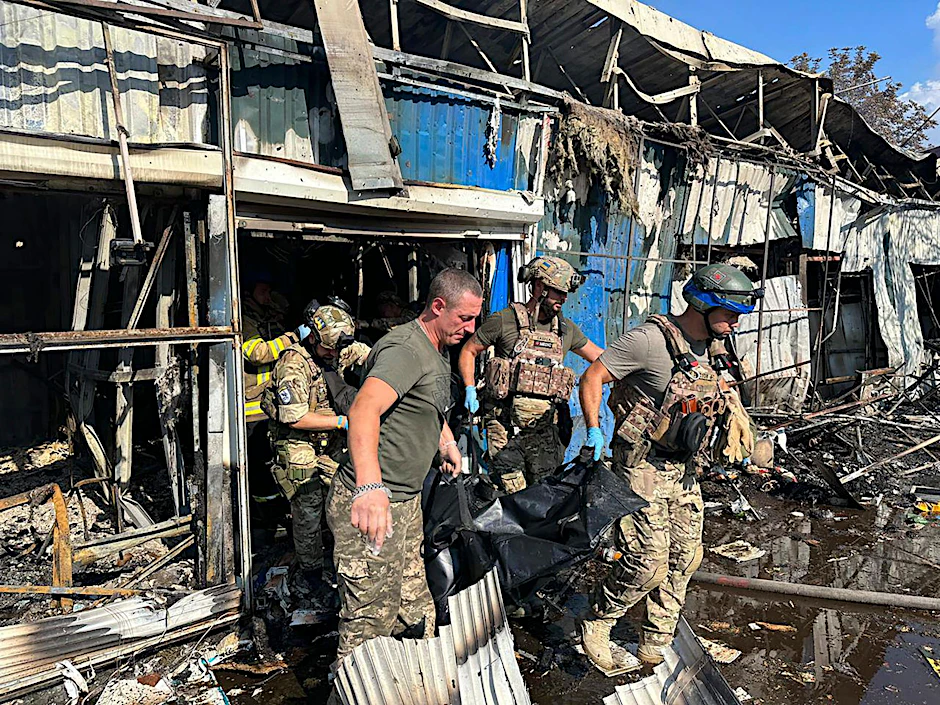 Soldaten und Rettungskräfte tragen die Leiche eines Opfers nach einem russischen Raketenangriff auf einen Markt in der Region Donezk.