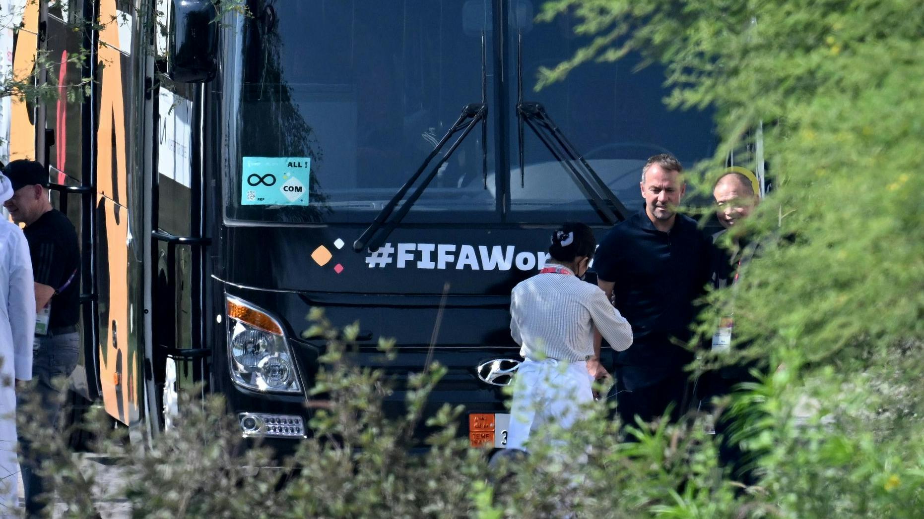 In der Wüste ab durch die Hecke: Hansi Flick vorm Teambus, bevor dieser Deutschland aus dem WM-Quartier in Katar Richtung Heimflug bringt.