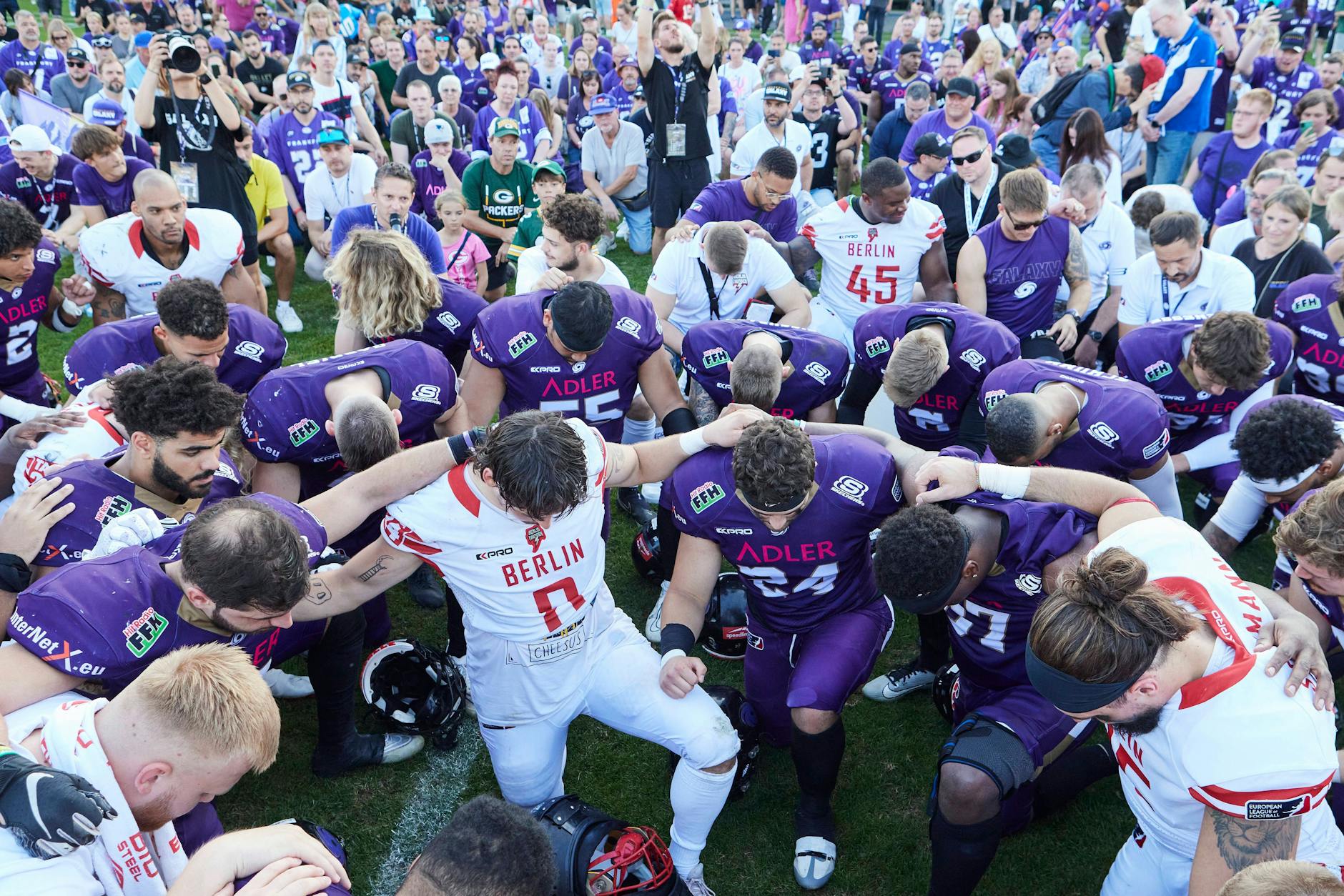 Huddle für die verletzten Berliner: Die Footballer von Berlin Thunder und Frankfurt Galaxy versammeln sich am Mittelkreis und werden von Zuschauern umringt.