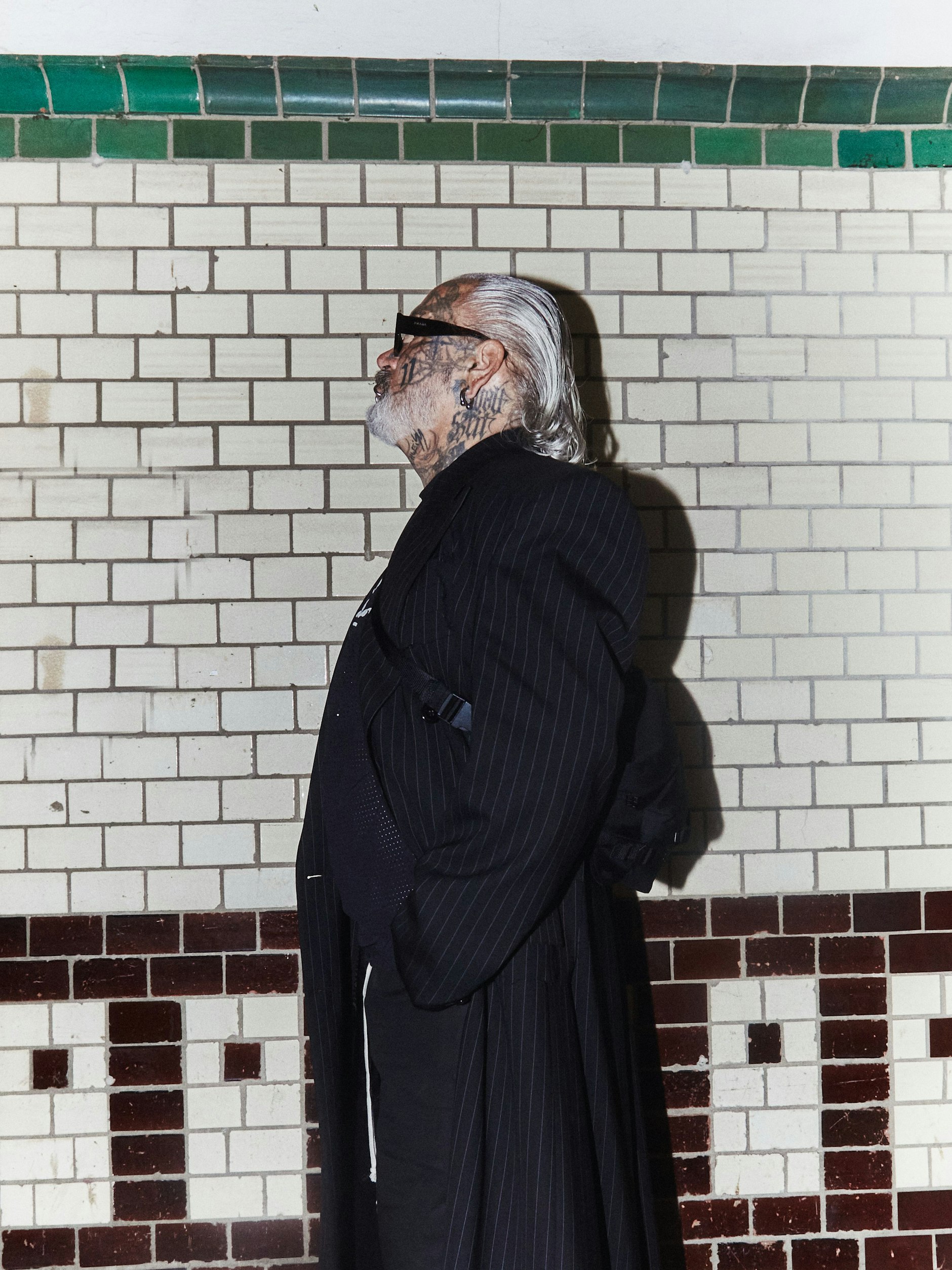 Unverkennbar Marquardt: Wet Look und Sonnenbrille (von Prada). Dazu trägt der Berliner Fotograf einen Nadelstreifenmantel von Vetements und Cowboystiefel von Dries Van Noten. Top und Shorts: Rick Owens x Champion.