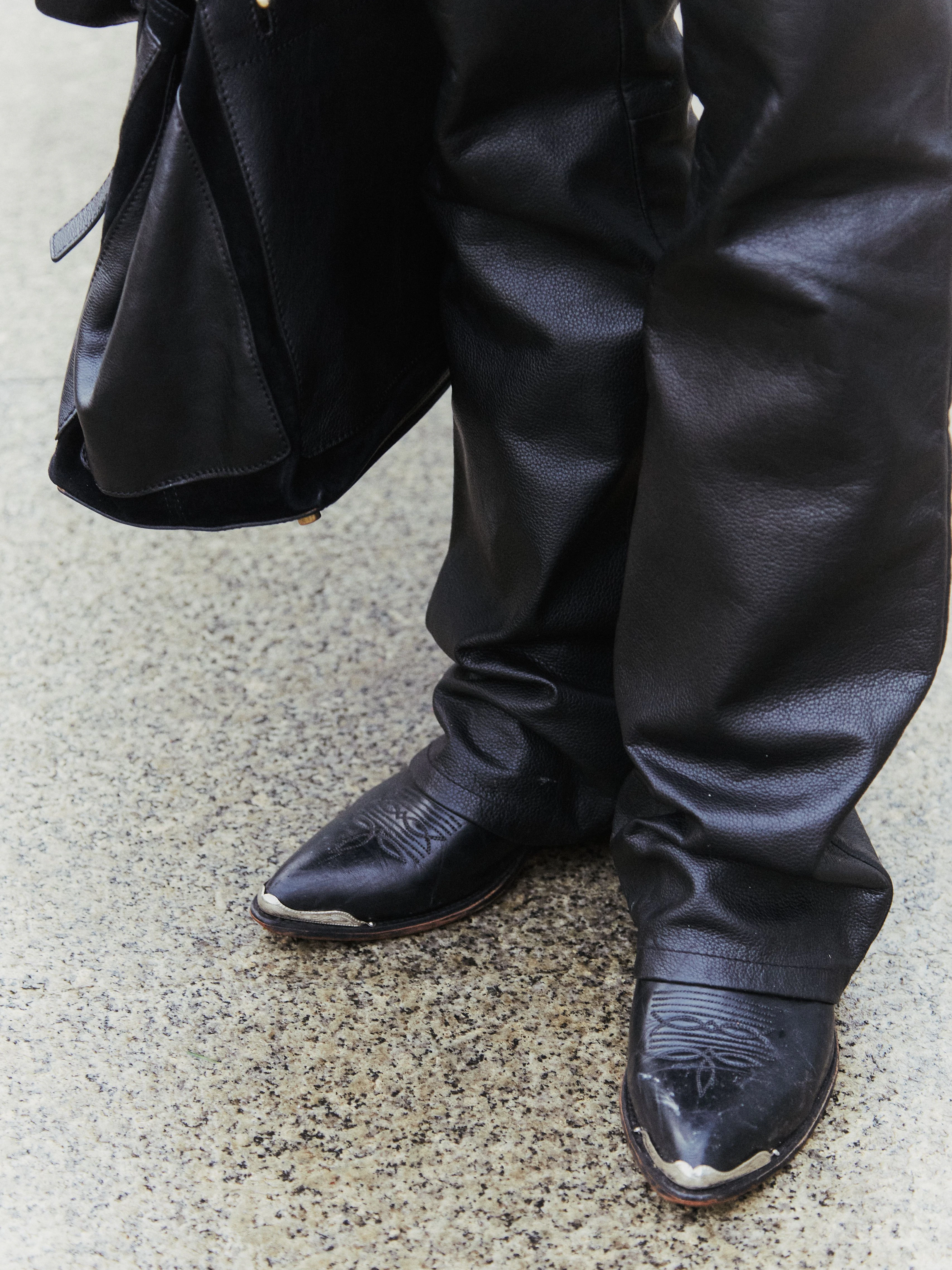 Trendige Cowboystiefel auf nassem Asphalt.