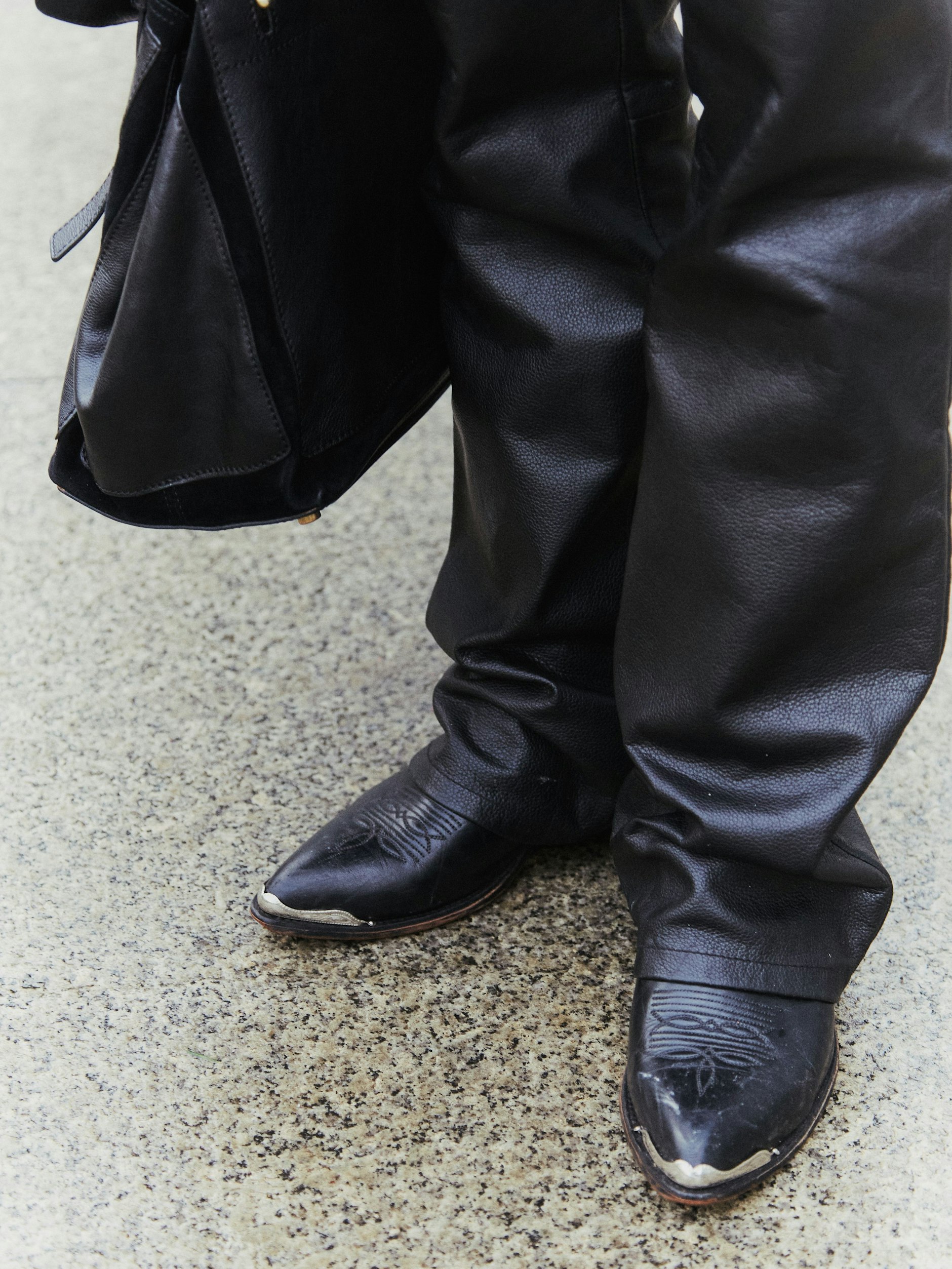 Trendige Cowboystiefel auf nassem Asphalt.