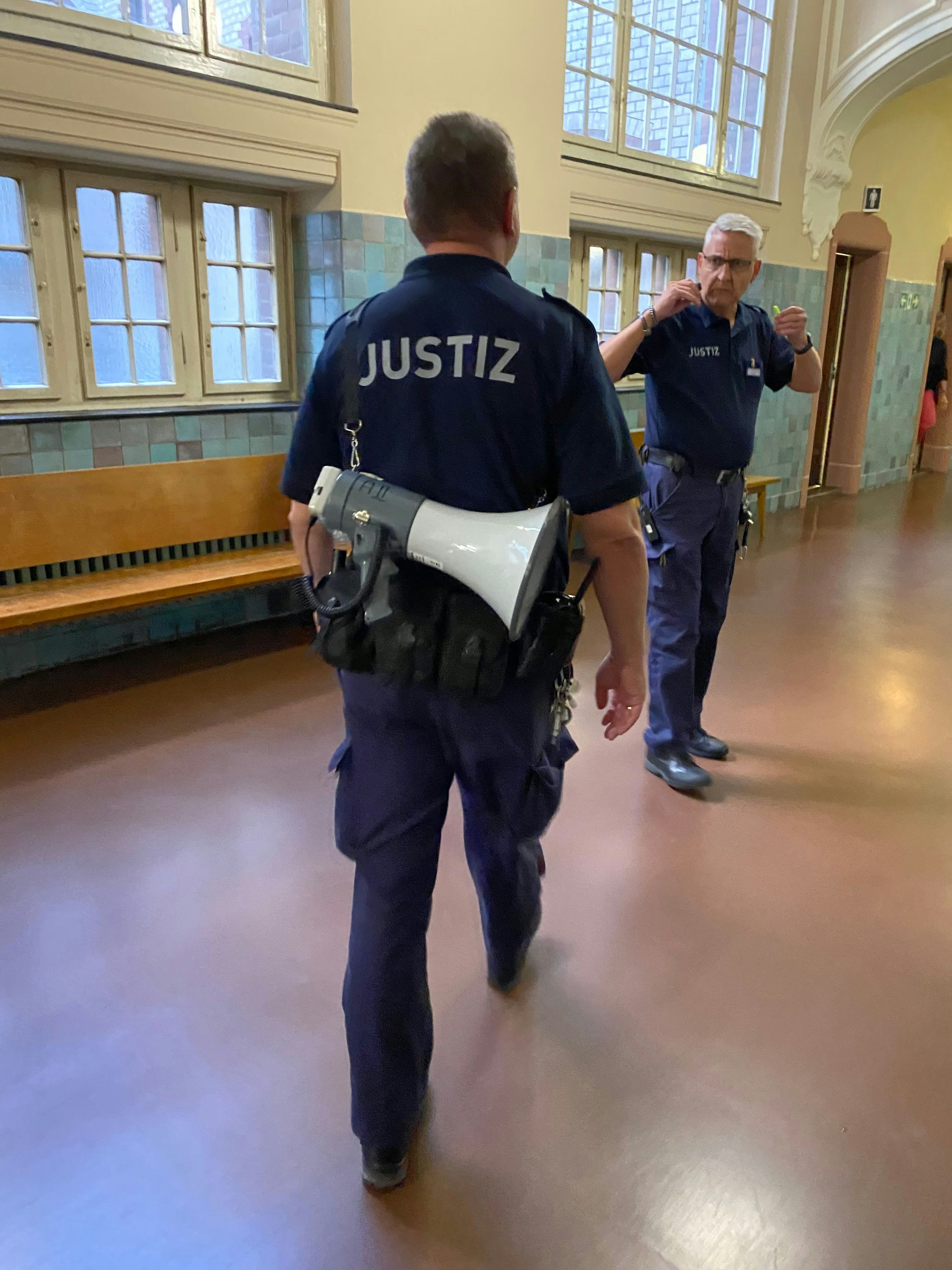 Wachtmeister laufen im Kriminalgericht mit Megafonen umher.
