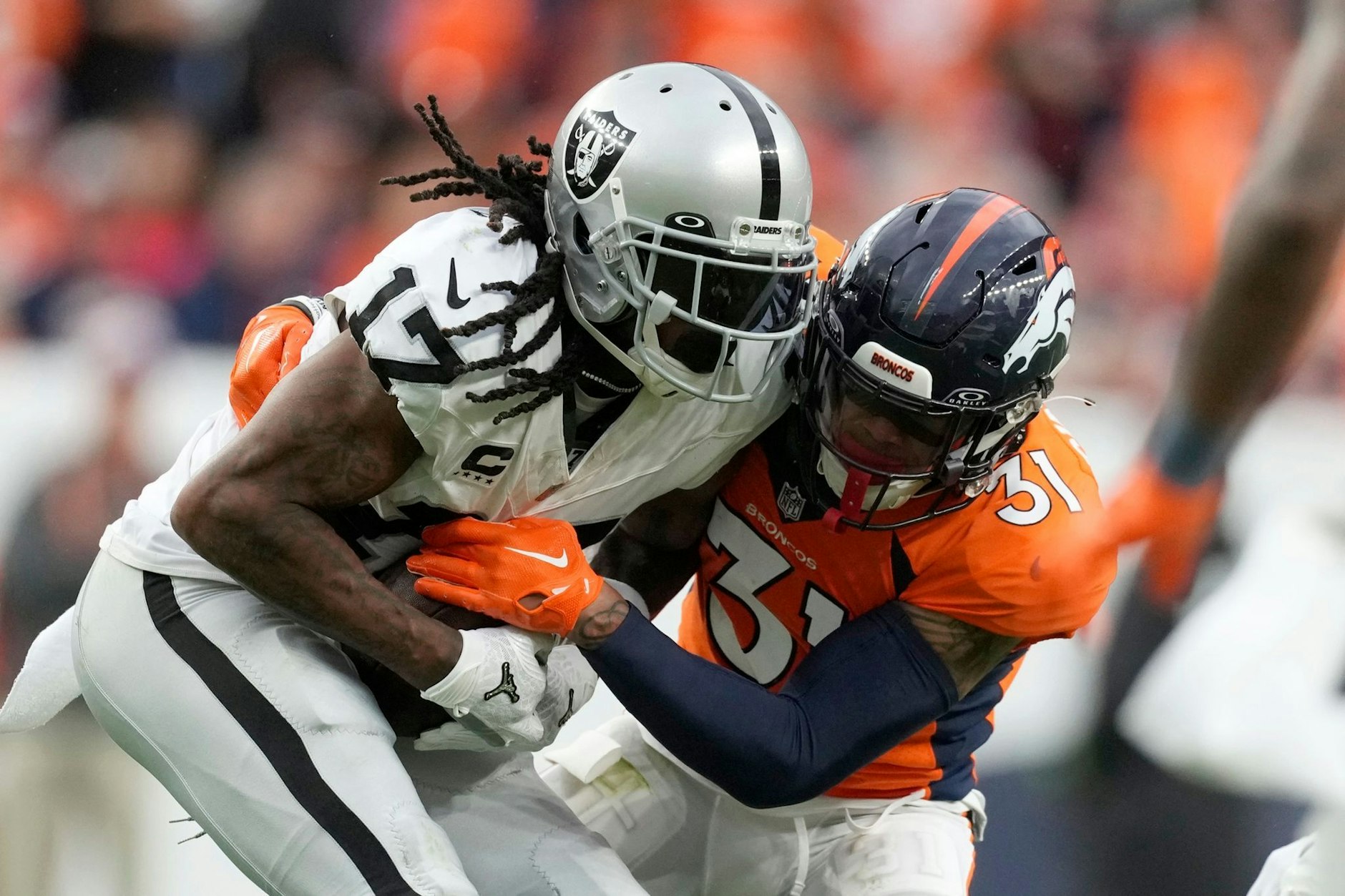 Davante Adams (17), Wide Receiver der Las Vegas Raiders, wird in der zweiten Hälfte von Justin Simmons (31), Safety der Denver Broncos, angegriffen.  