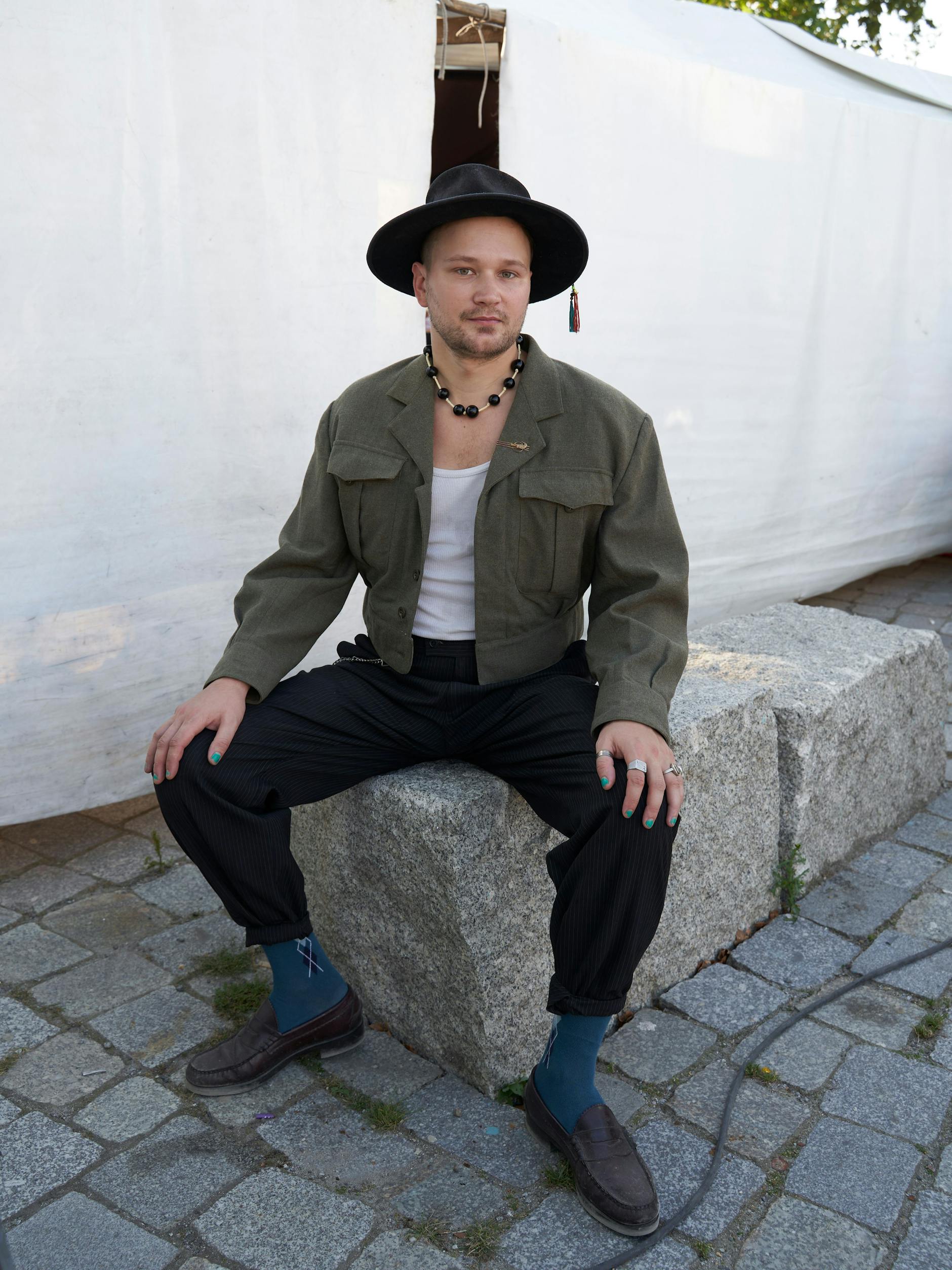 Neels ist Künstler, genauer gesagt Maler, ganz ordentlich und akademisch in Weißensee ausgebildet. Auch er sammelt seine Kleidung vornehmlich aus den „zum Mitnehmen“-Kartons am Straßenrand; so auch das Top und die Hose, die er heute trägt. Seine außergewöhnliche Jacke habe er von einer Bekanntschaft, die über das Kleidungsstück zur Freundschaft wurde. Jener Freund schneiderte seine aussortierte Militärjacke einst für Neels um. Auch die Schuhe sind ein Geschenk. Die auffällige Kette, die Neels um den Hals trägt, hing an einem Baum. „Die habe ich mir zurechtgebastelt“, sagt er.