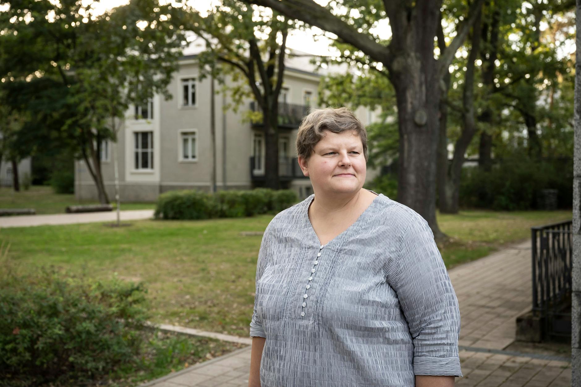Neoklassizistische Gebäude unter hohen Bäumen: Sabrina Knüppel auf dem Gelände des früheren DDR-Vorzeigekinderheims in der Südostallee in Treptow. Heute leben hier wieder Mädchen und Jungen, aber mit ihren Eltern.