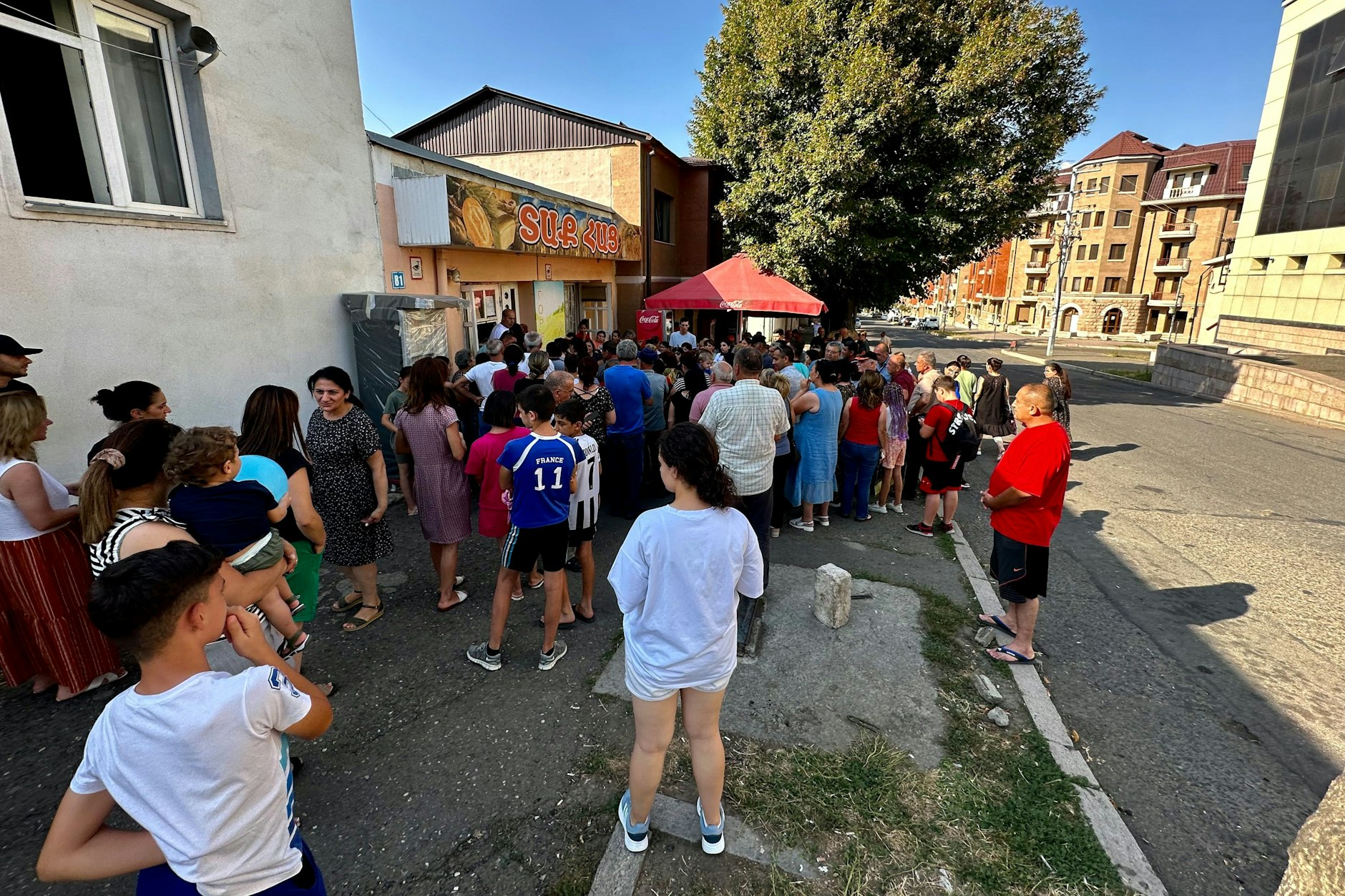 Menschen stehen vor einer Bäckerei um Brot an.