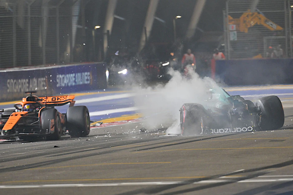 Nach einem Unfall steigt aus dem Auto von Lance Stroll (r) Rauch auf, während Oscar Piastri an der Unfallstelle vorbeifährt.  a
