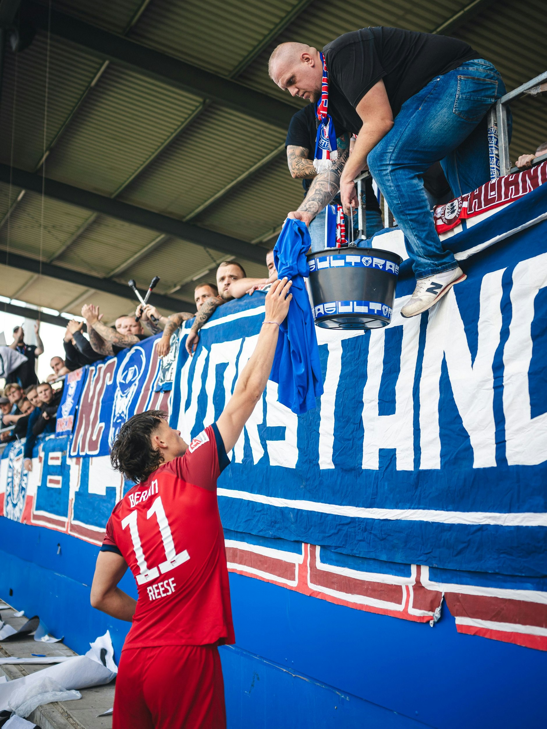 Fabian Reese übergibt die Spenden der Hertha-Fans für den an Lymphdrüsenkrebs erkrankten 16-jährigen Kiel-Fan an die Anhänger von Holstein.