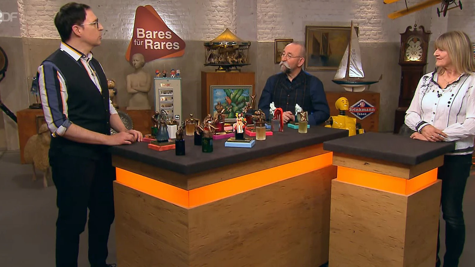 Der „Bares für Rares“-Experte Colmar Schulte-Goltz, der Moderator Horst Lichter und die Verkäuferin Erika mit der duftenden Kunstsammlung