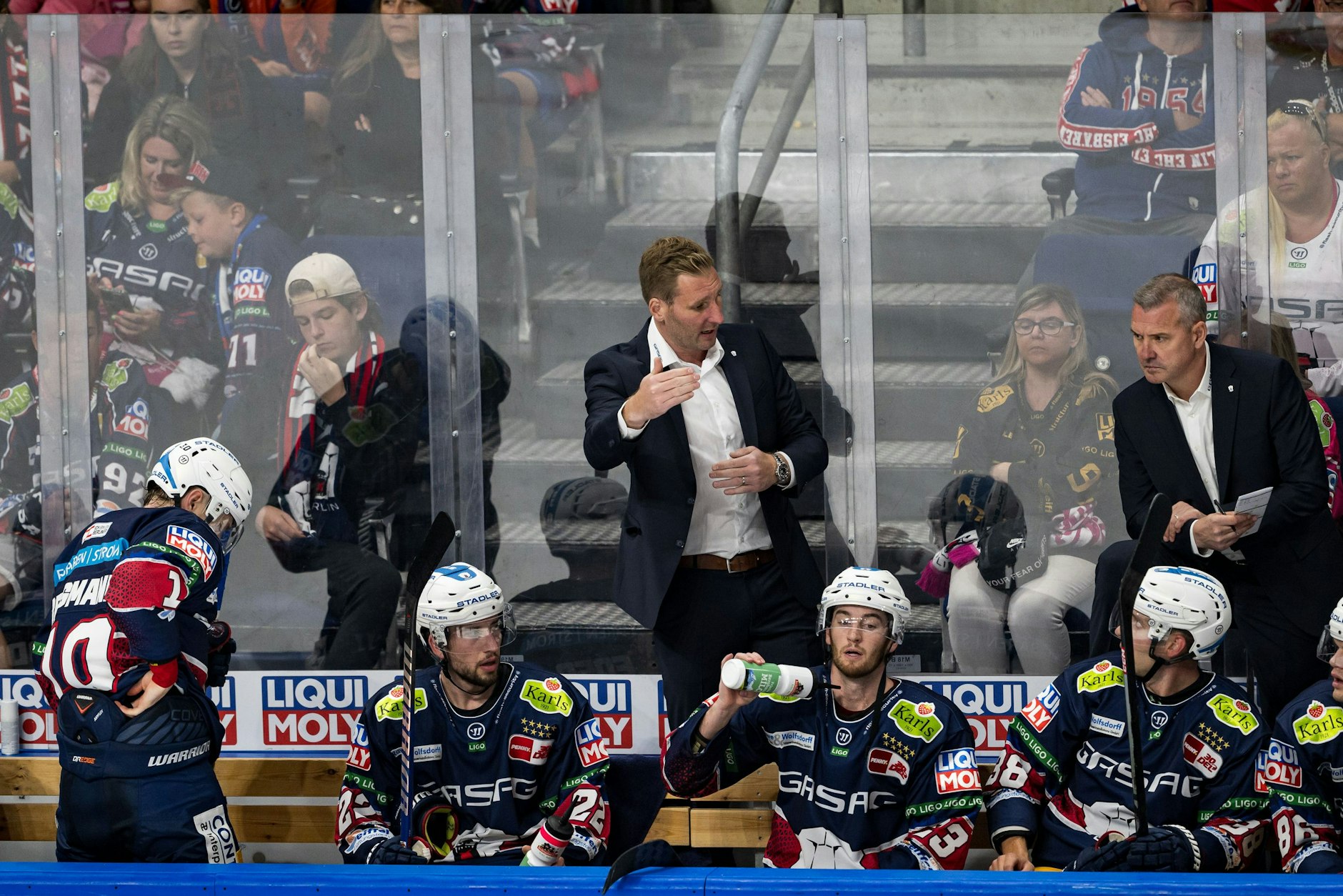 Eisbären-Co-Trainer André Rankel (Mitte) gestikuliert während des Spiels hinter der Bande.